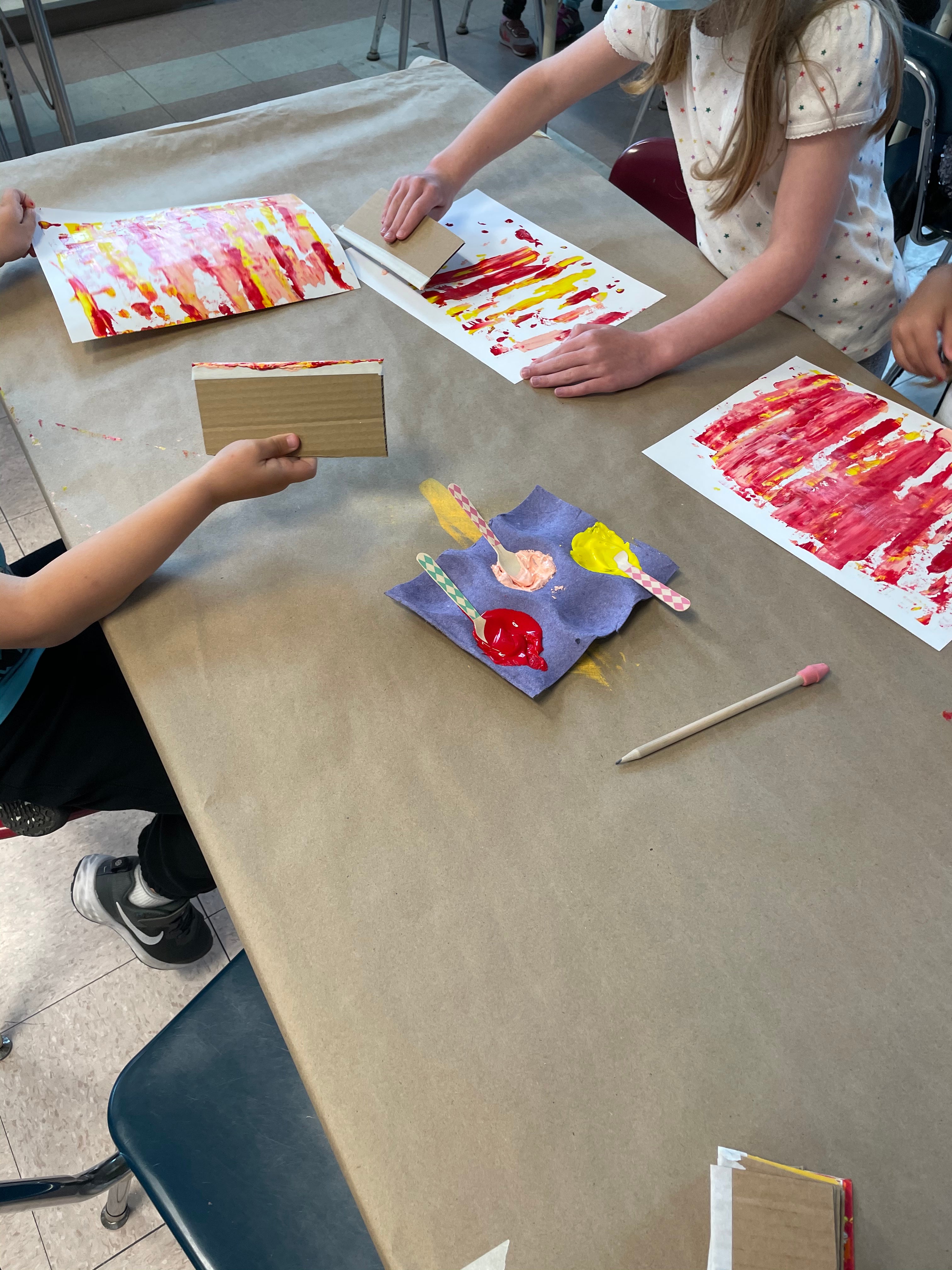 Students applying paint using wooden spoons and spreading it out to created the squeegee effect.  
