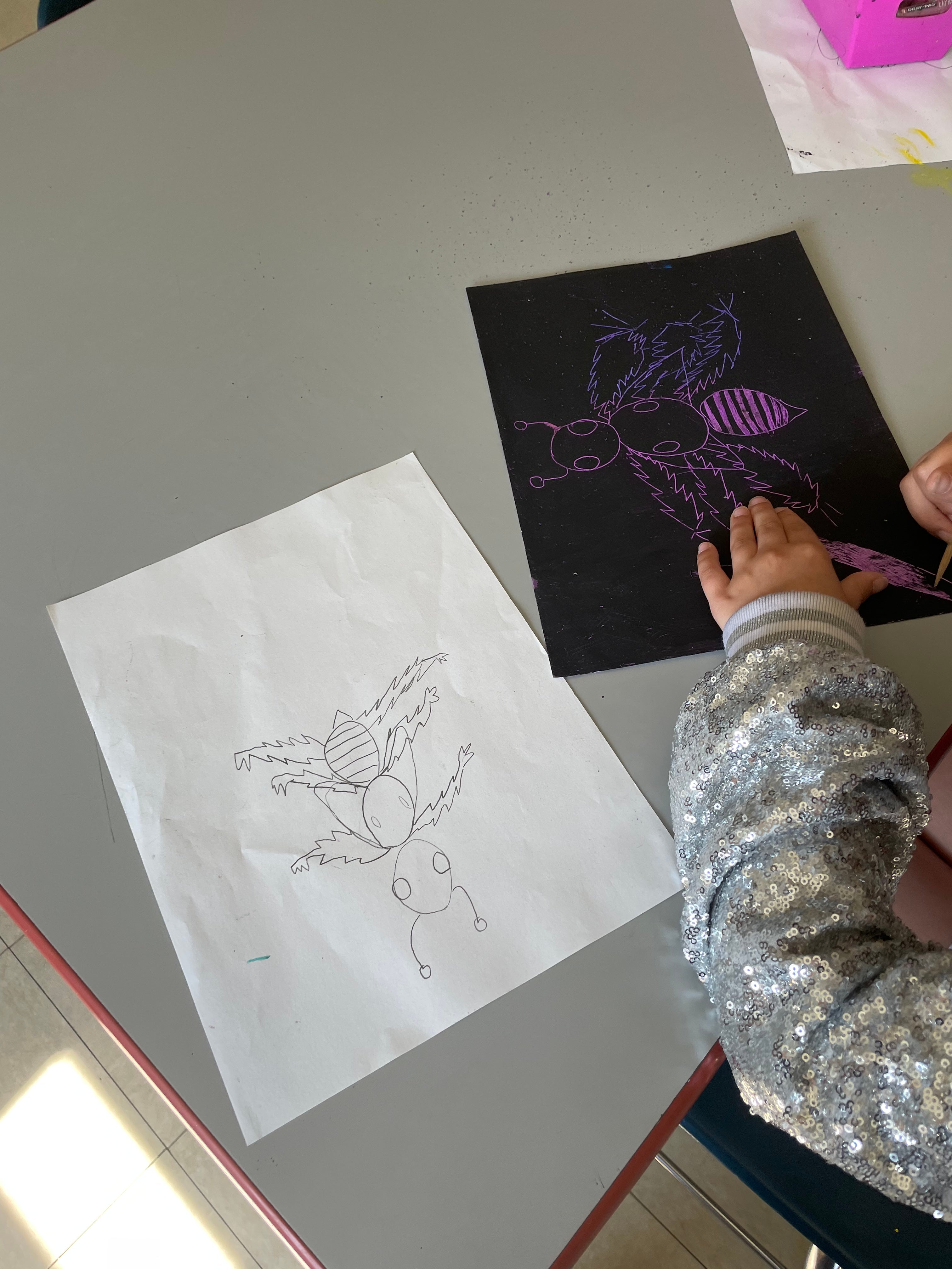 Students use wooden tools to etch into their tempera paint, uncovering color underneath the surface to create an insect with lines. 