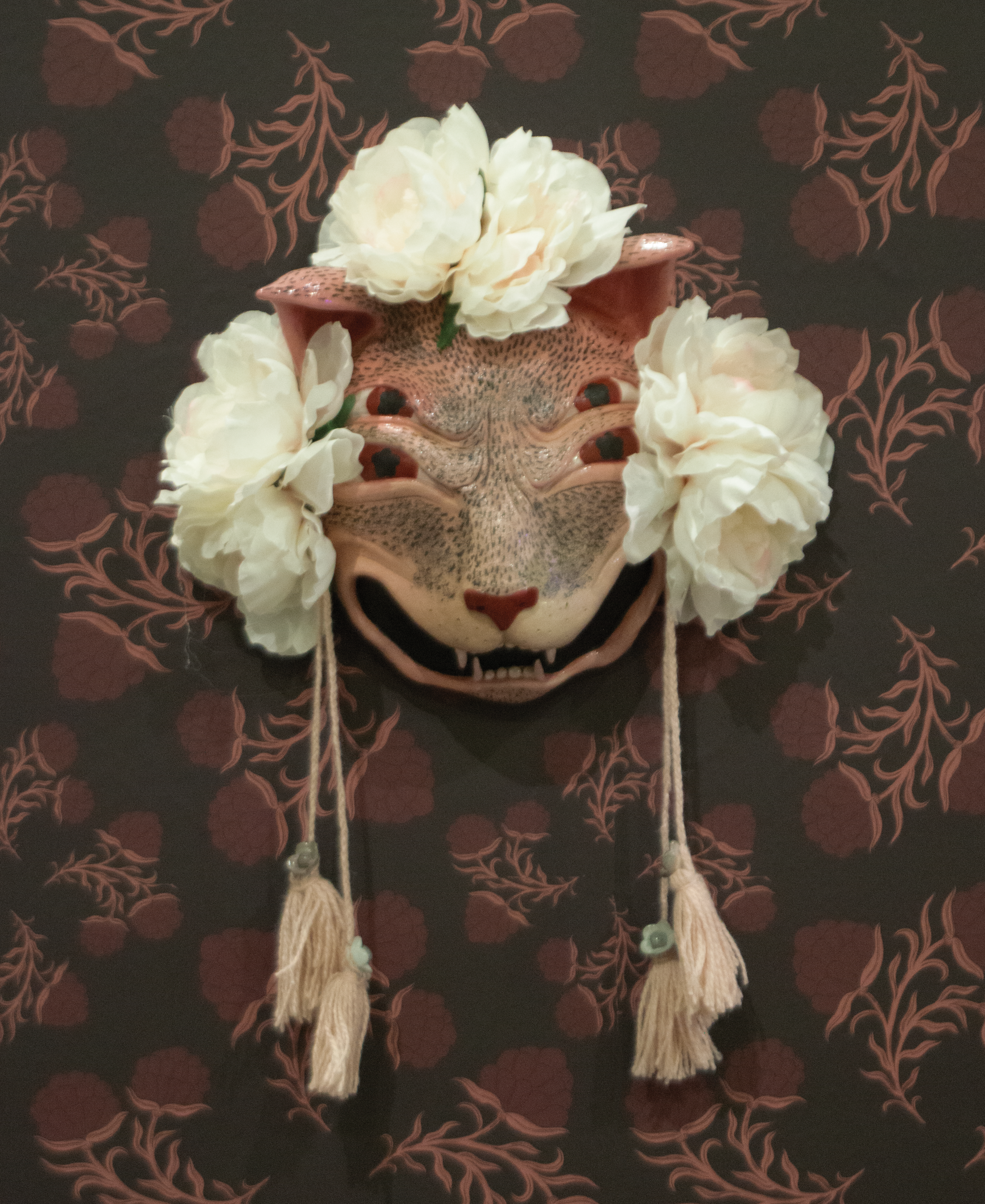 Pink ceramic mask of yowling cat with four eyes.