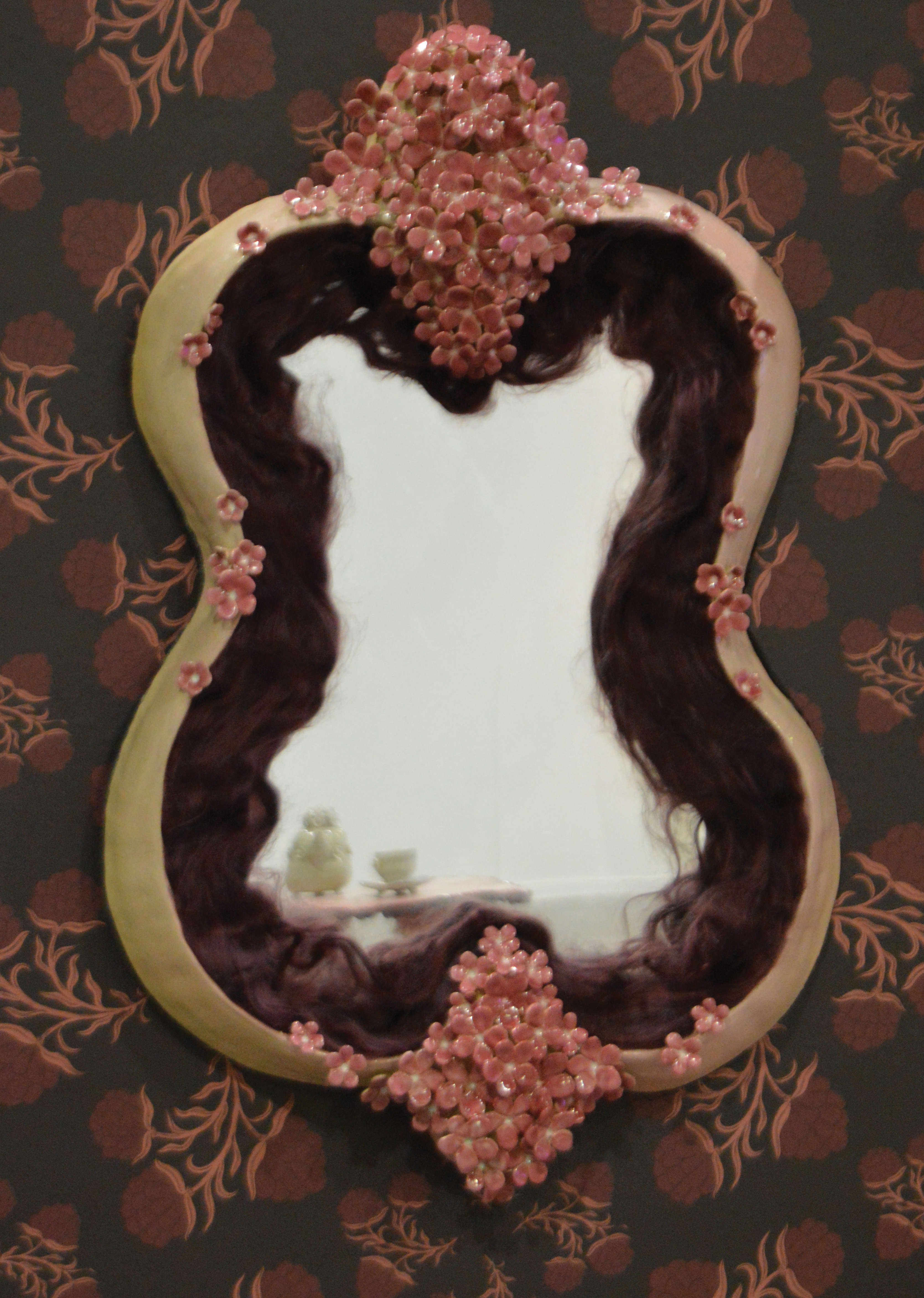 Pink flower ceramic frame around funhouse mirror.