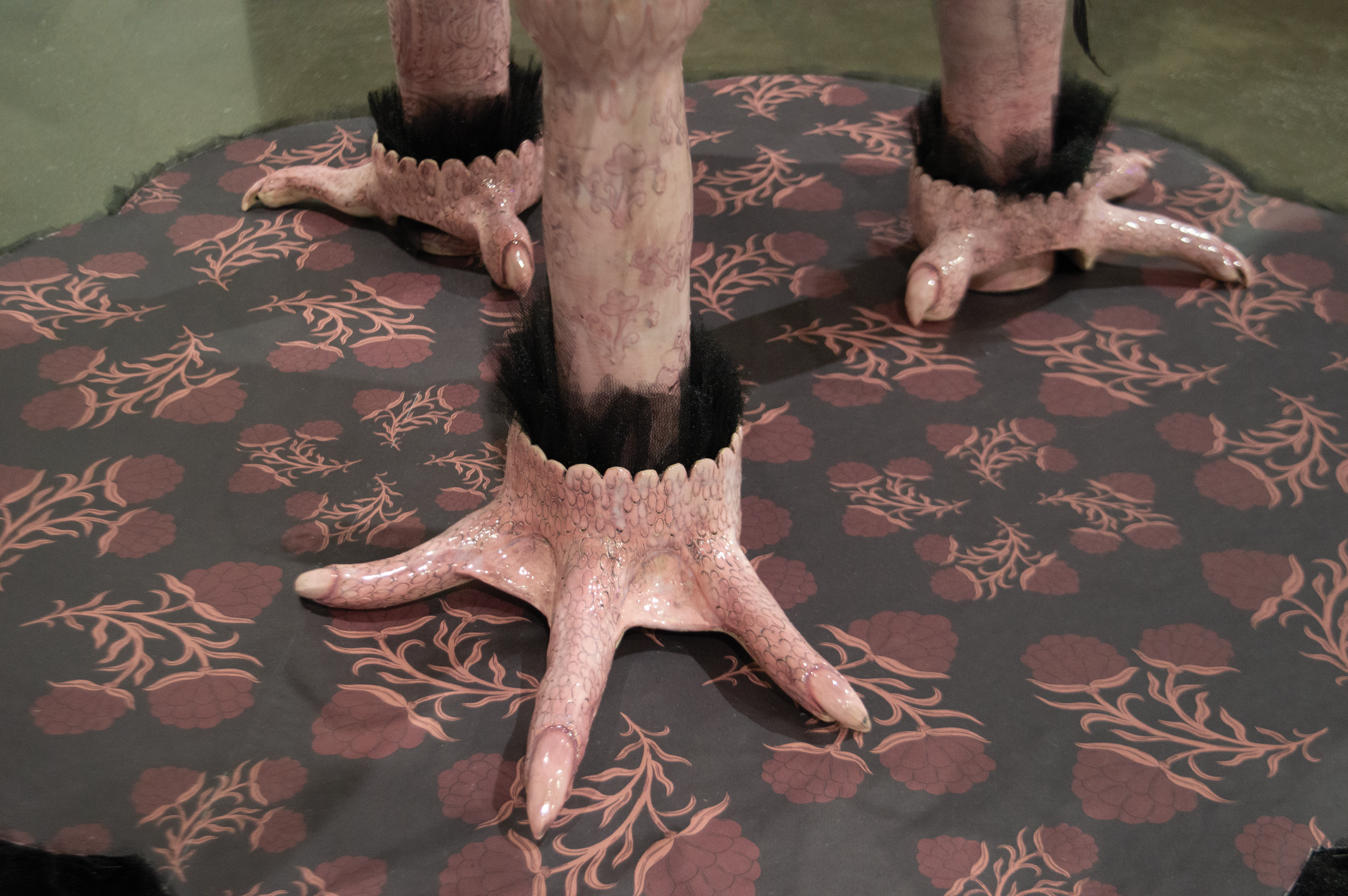 Pink ceramic chicken feet at the base of a ceramic chair.