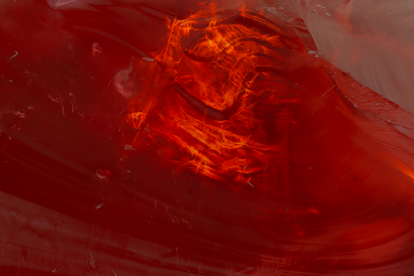 Close-up image of a red gem, with swirling patterns of light.