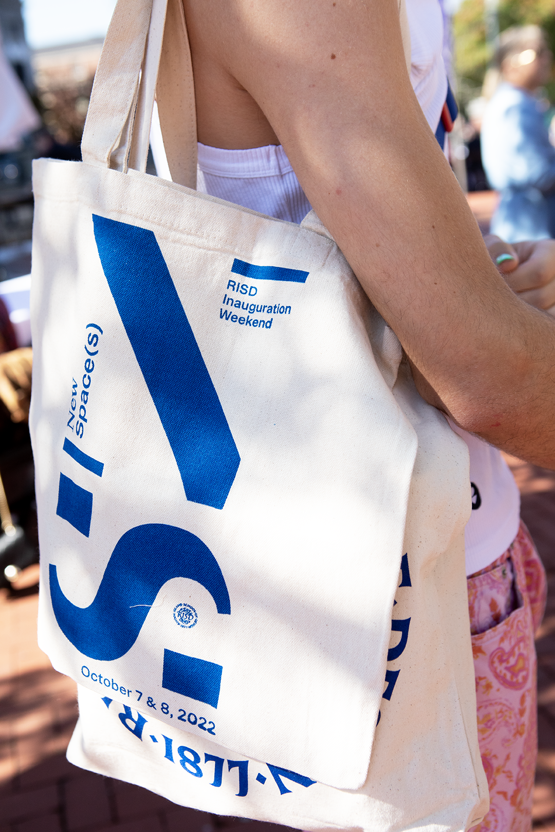 /Close-up%20of%20a%20young%20white%20woman%20holding%20a%20canvas%20tote%20with%20the%20letters%20N%20and%20S%20in%20blue