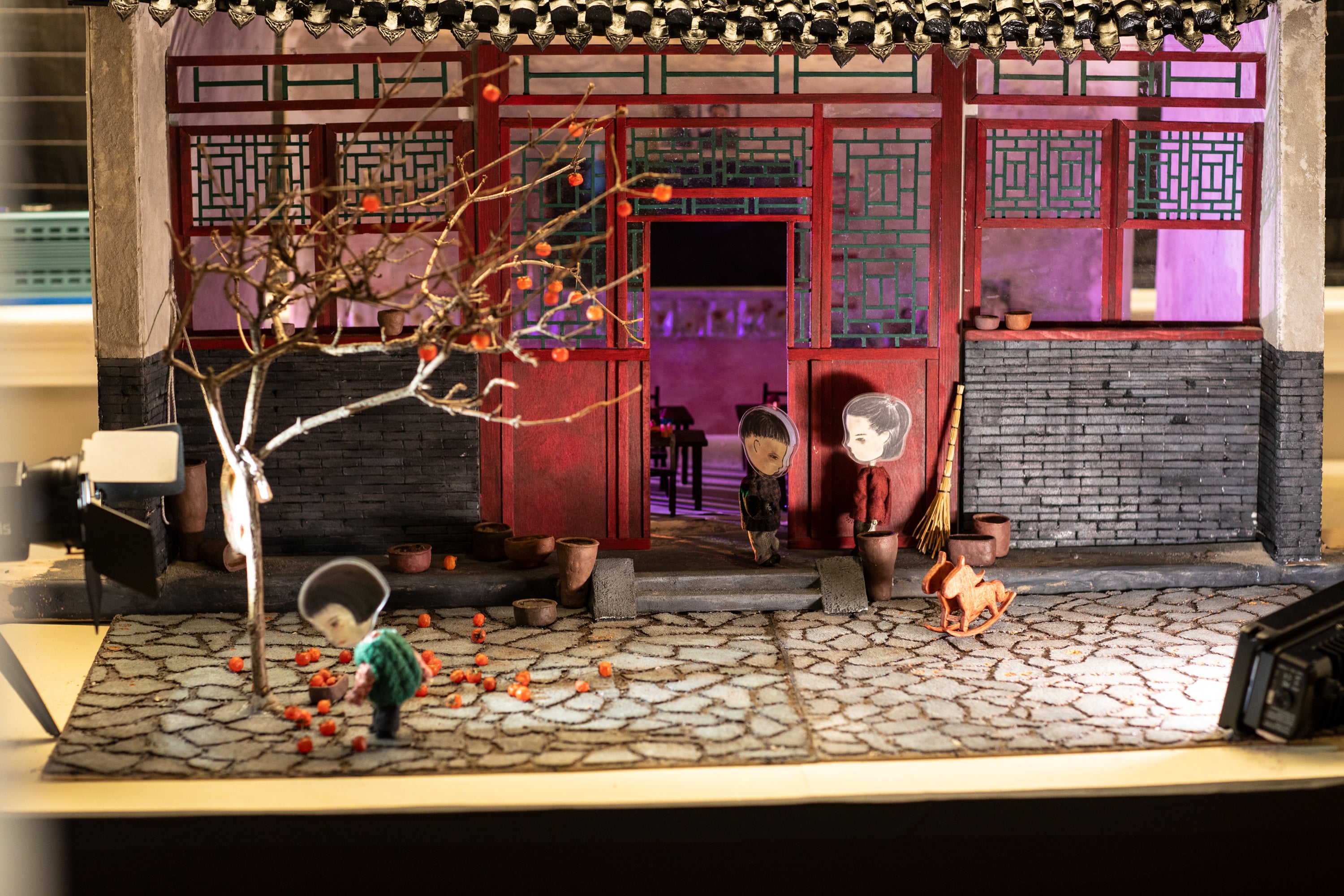 /Small%20diorama%20set%20of%20a%20scene%20outside%20a%20house%20with%20Asian%20style%20architecture.%20In%20the%20foreground%2C%20and%20young%20girl%20figure%20picks%20up%20persimmons.%20