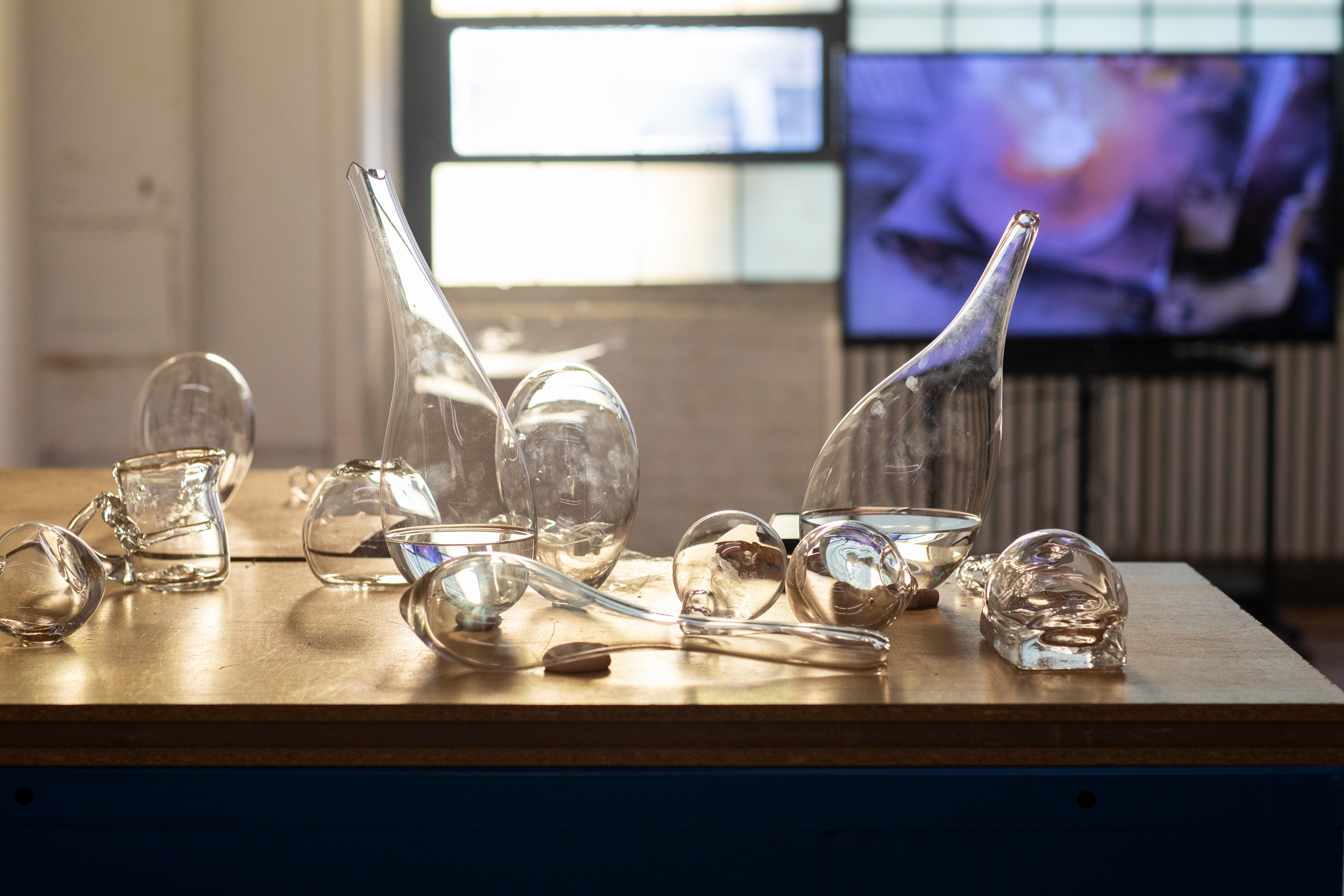 /Examples%20of%20blown%20glass%20vessels%20sit%20on%20a%20wooden%20table%20top.