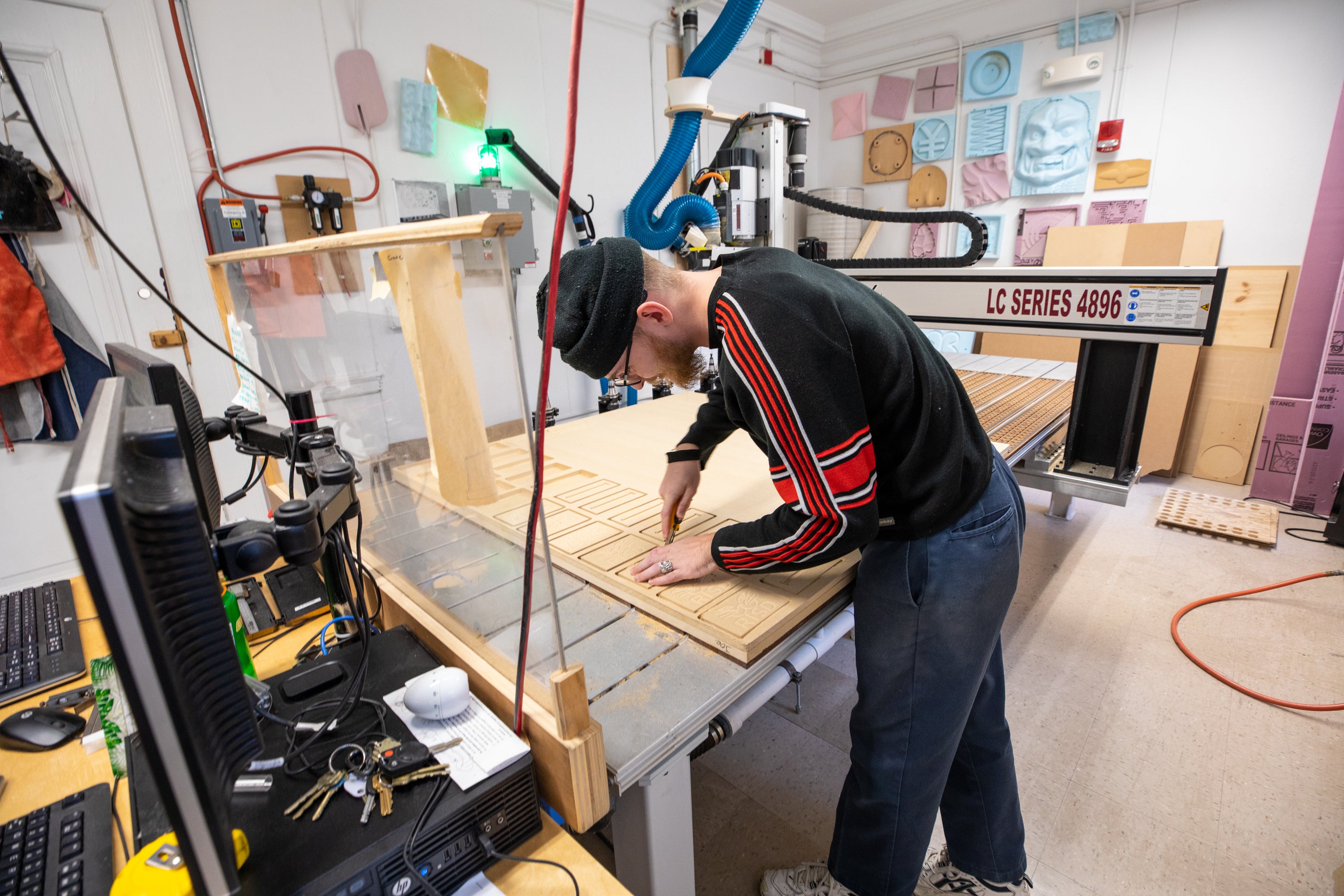 /Student%20pulls%20out%20pieces%20of%20MDF%20cut%20by%20a%20large%20CNC%20machine.