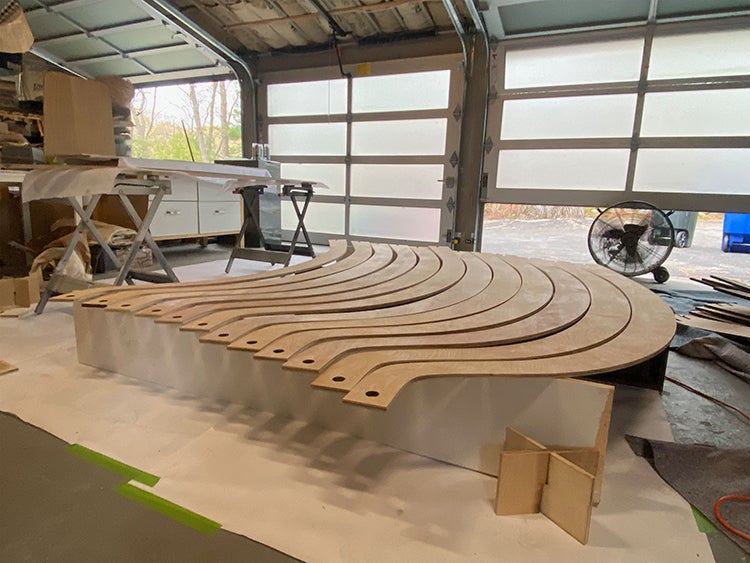 A garage with several curved wooden panels laying next to each other ready to be finished