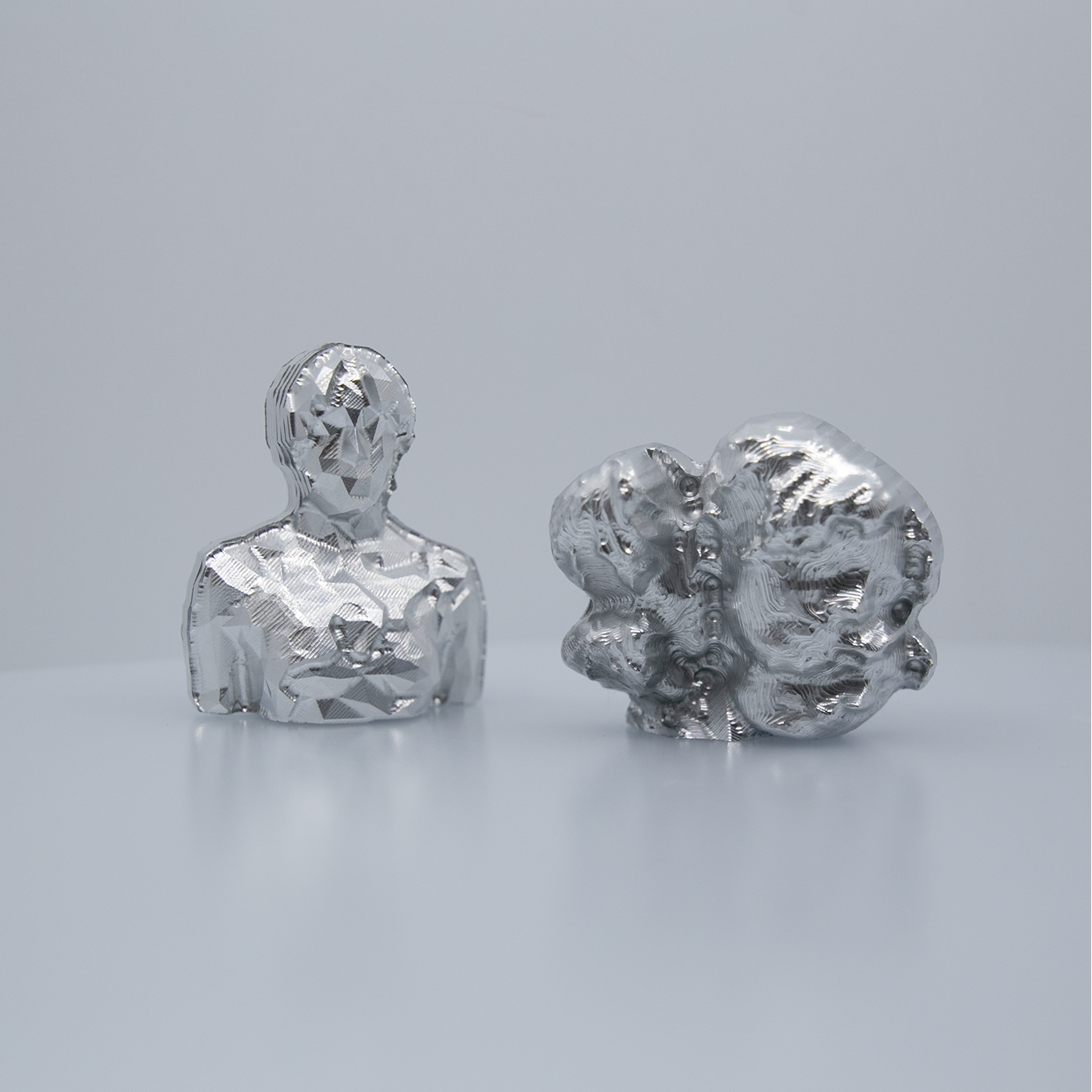 Two small metal sculptures sit next to each other.