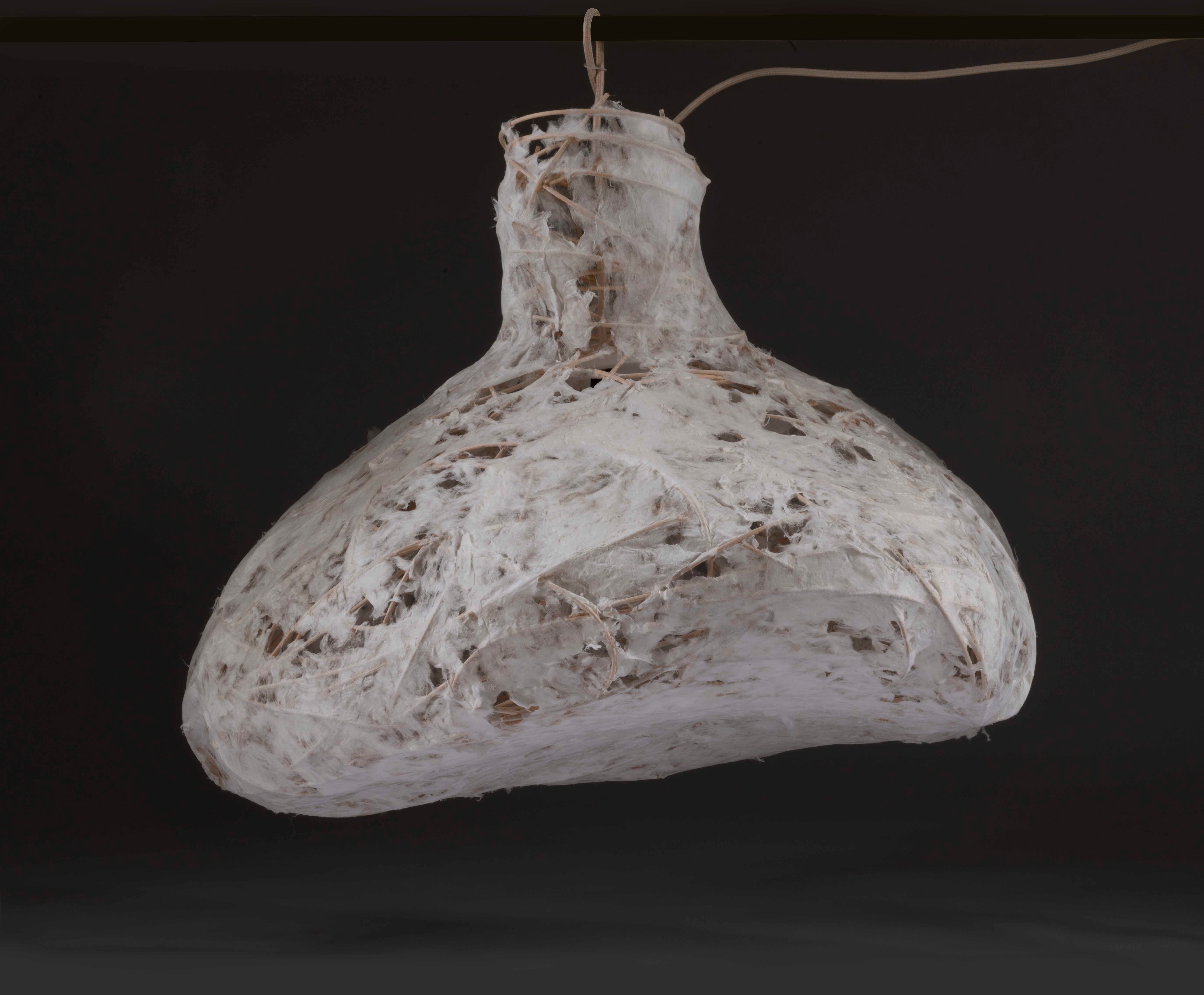 A pendant light born from weaving and coaxing dampened wood cord into place, with paper made directly on the surface of the structure.