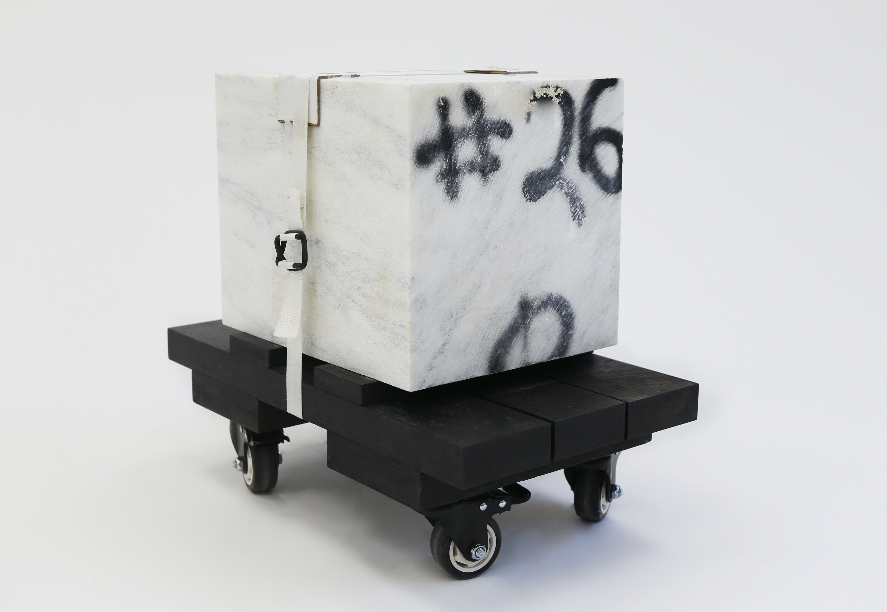 A meticulously cut block of white marble tightly bound with a crisp nylon packing strap.