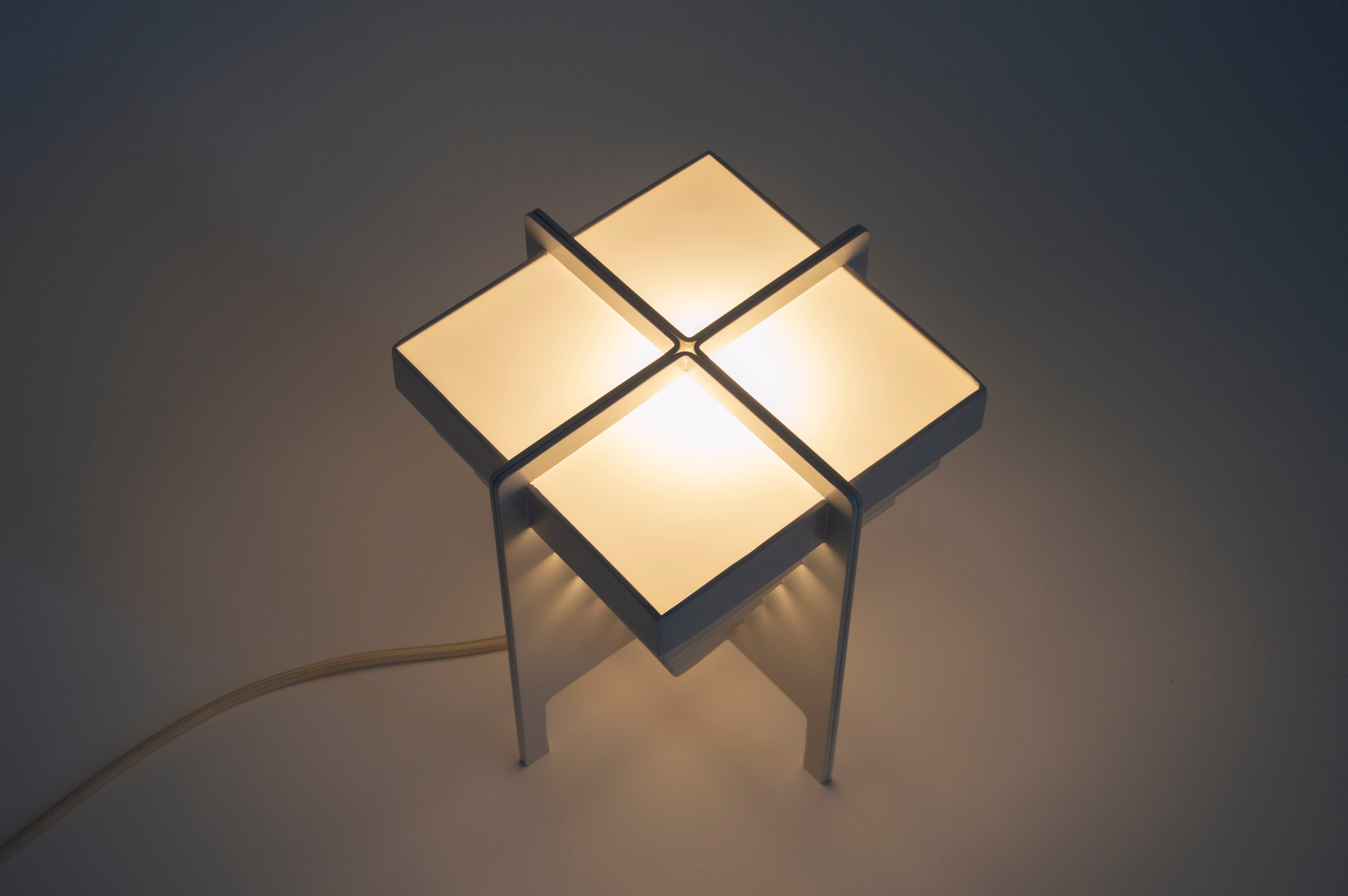 A lamp made of four repeated units and arranged in a way to emphasize the gap between the elements. 