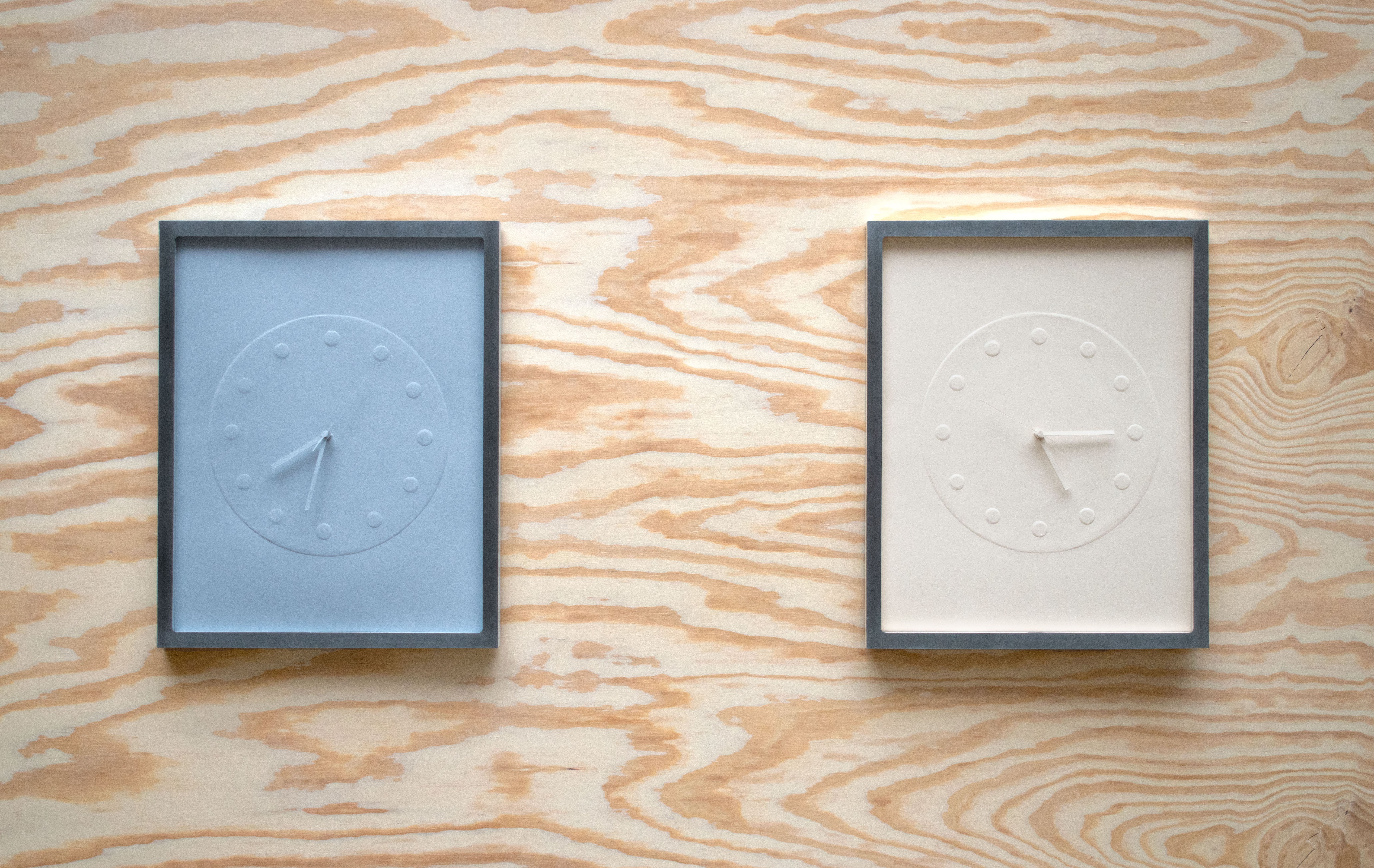 A clock made of embossed paper and presented in a custom frame.