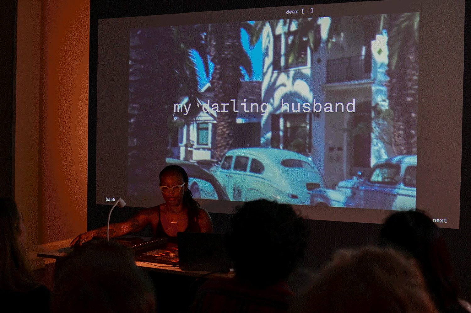 Zoe sitting in front of 3 projected screens operating the book