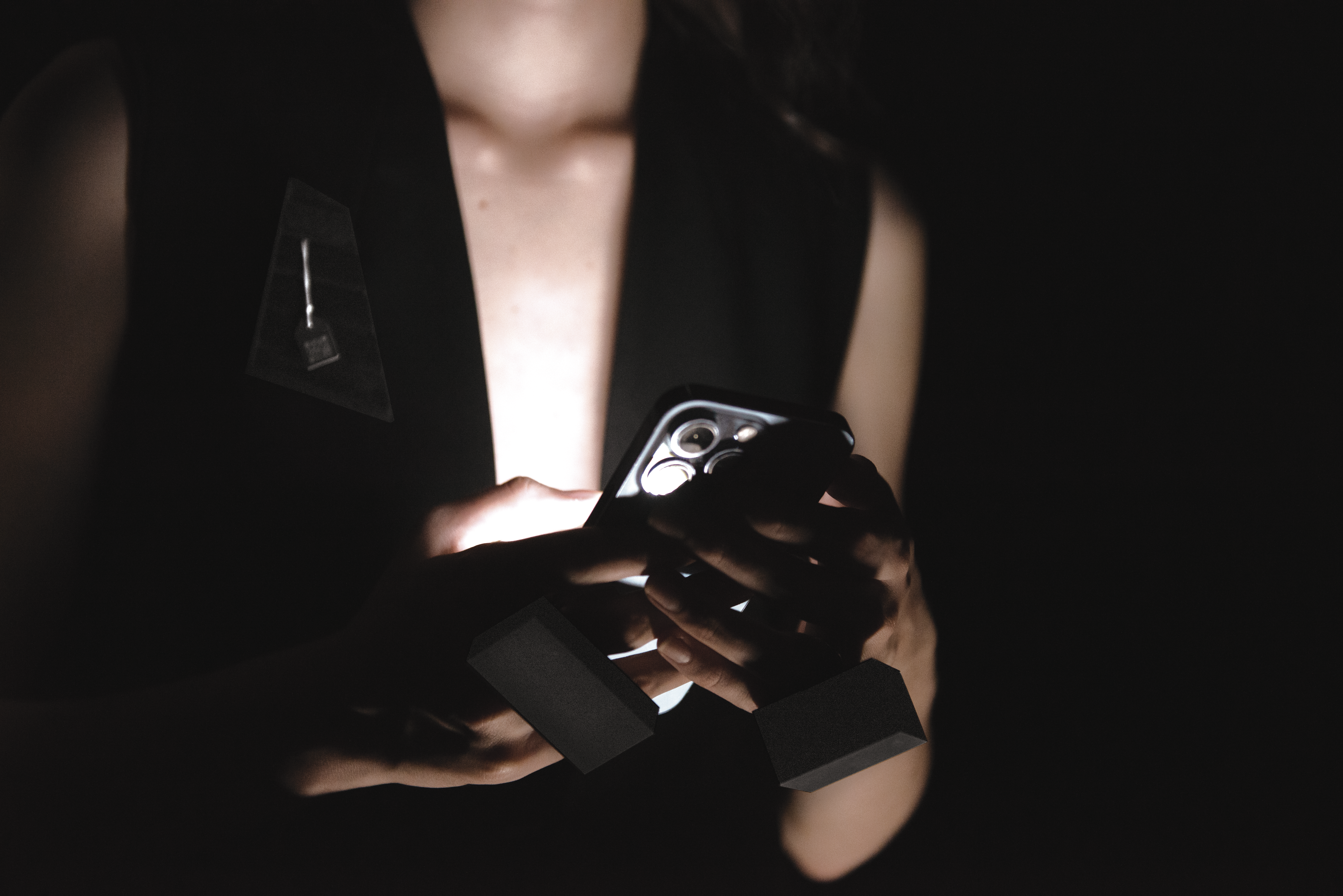 Model is wearing two rings and a brooch and holding the phone.