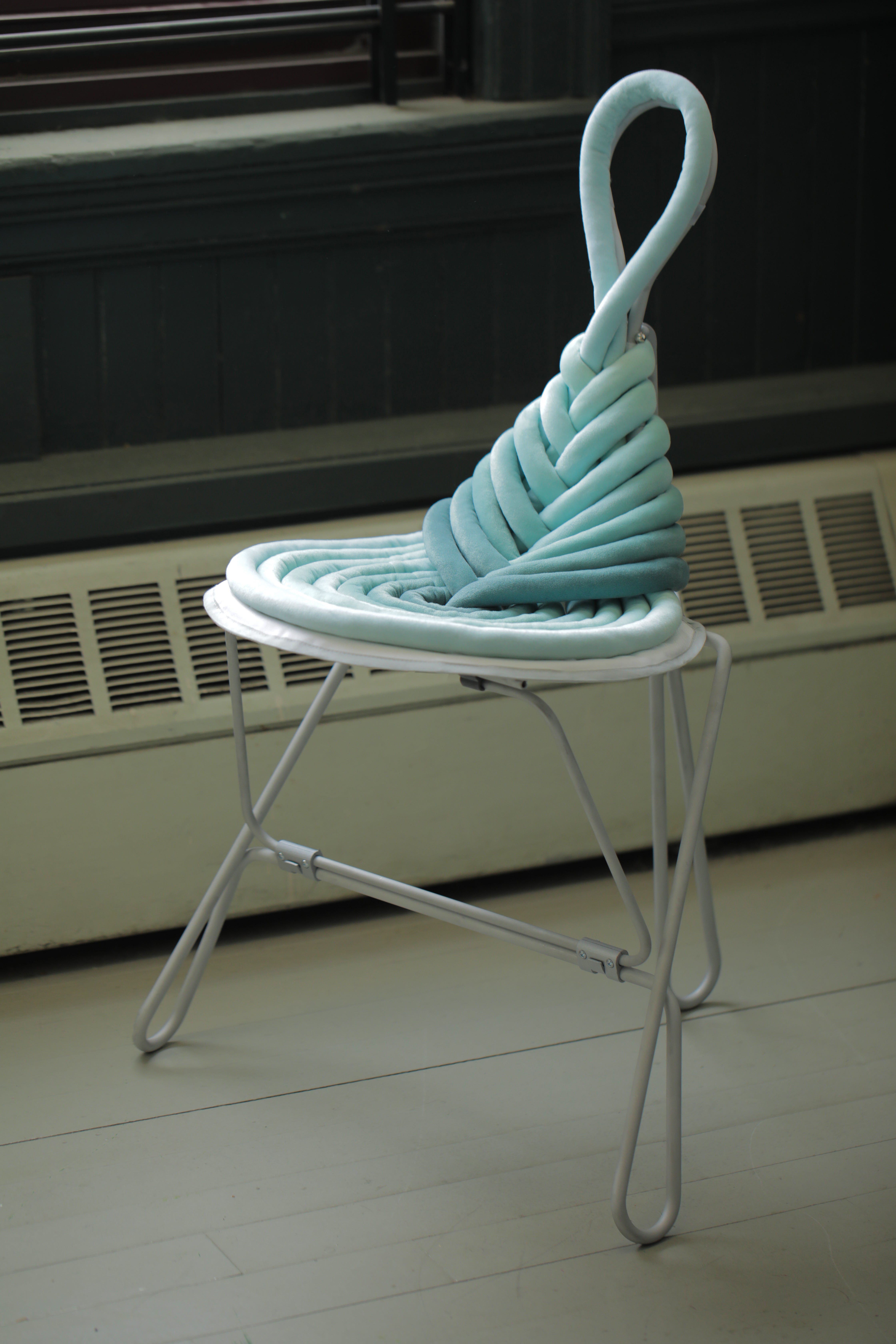 Green knot folding chair beside a window