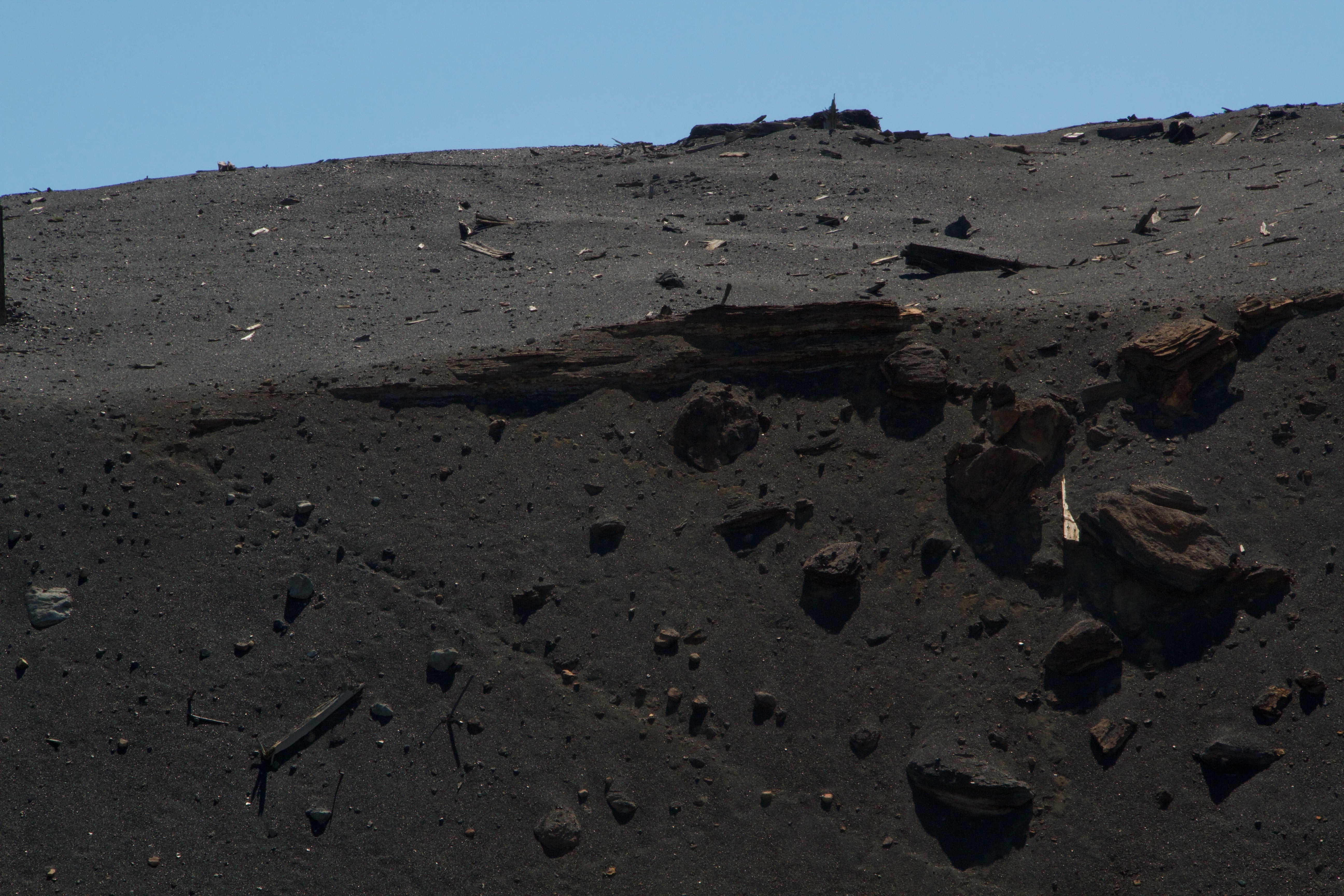 A spectral photograph of copper sulfide ore hovers in front of a greyscale background of glitched archival scans. The scans are nearly illegible but depict mining technology, the lower half of a Marcus Daly statue, and text from a Butte visitor's guide. 