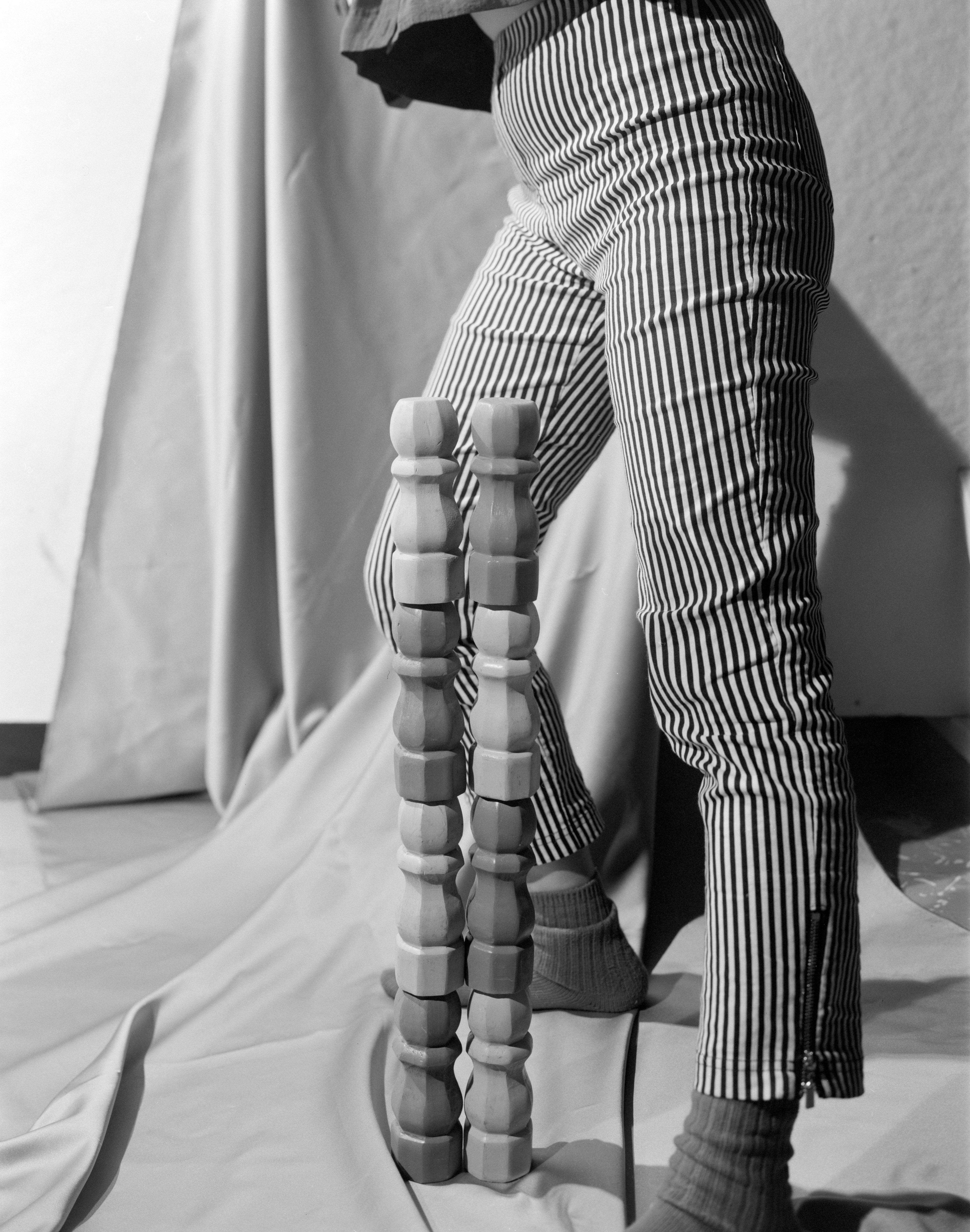 A figure standing in behind a wooden sculpture.