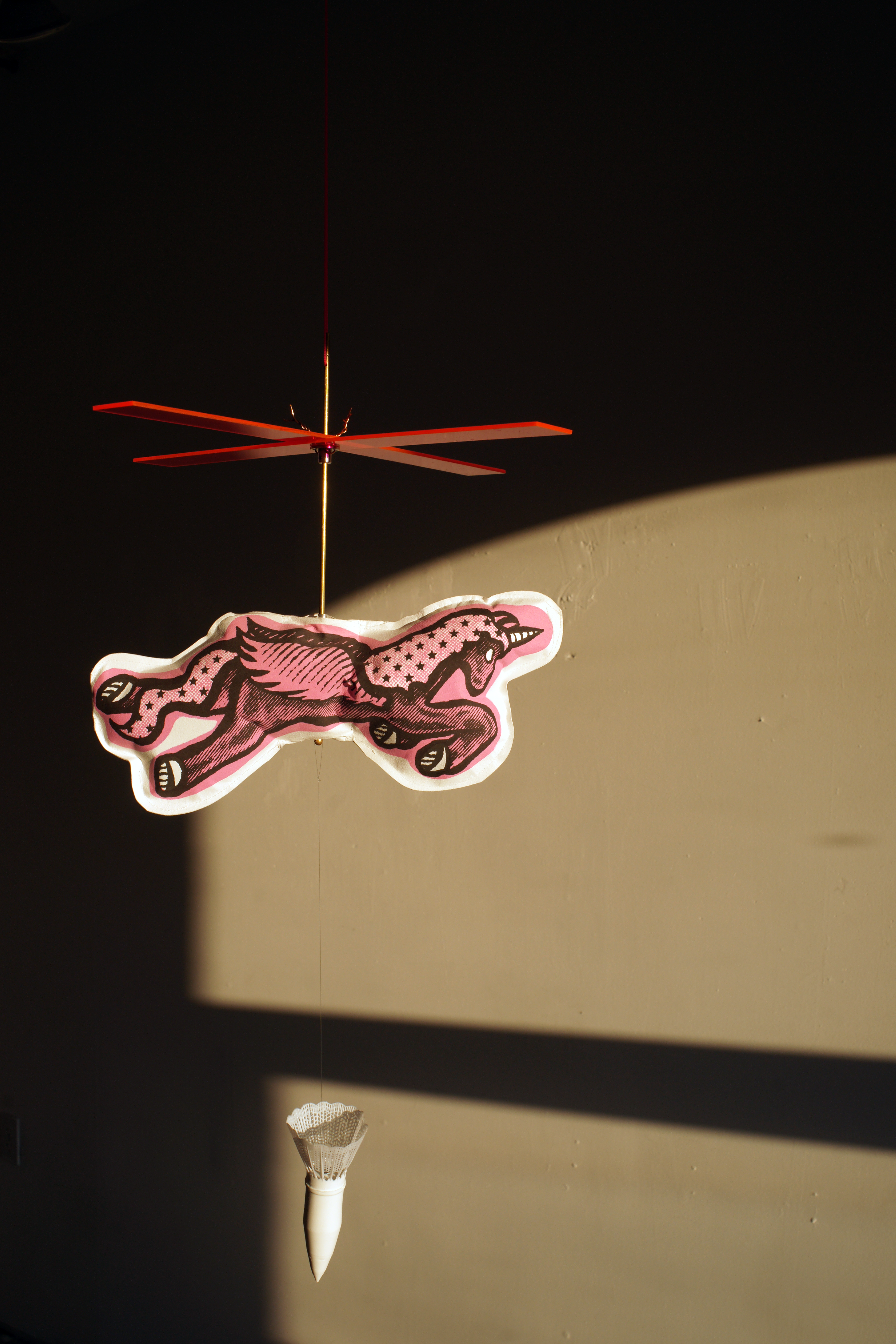 Unicorn with a pink helicopter propeller dropping a shuttlecock munition.