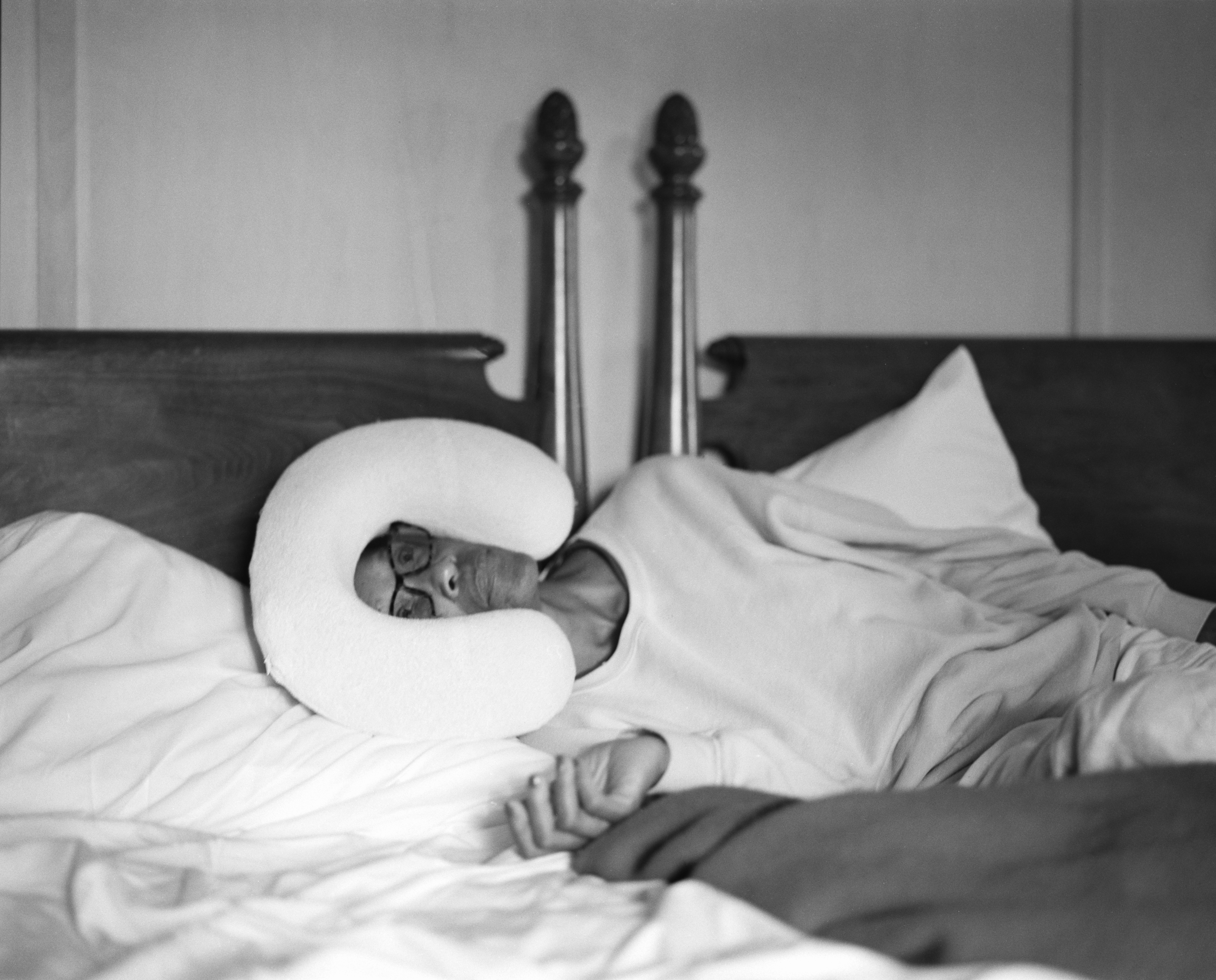 a woman lays on her side on a bed facing the camera, something strange is on her head