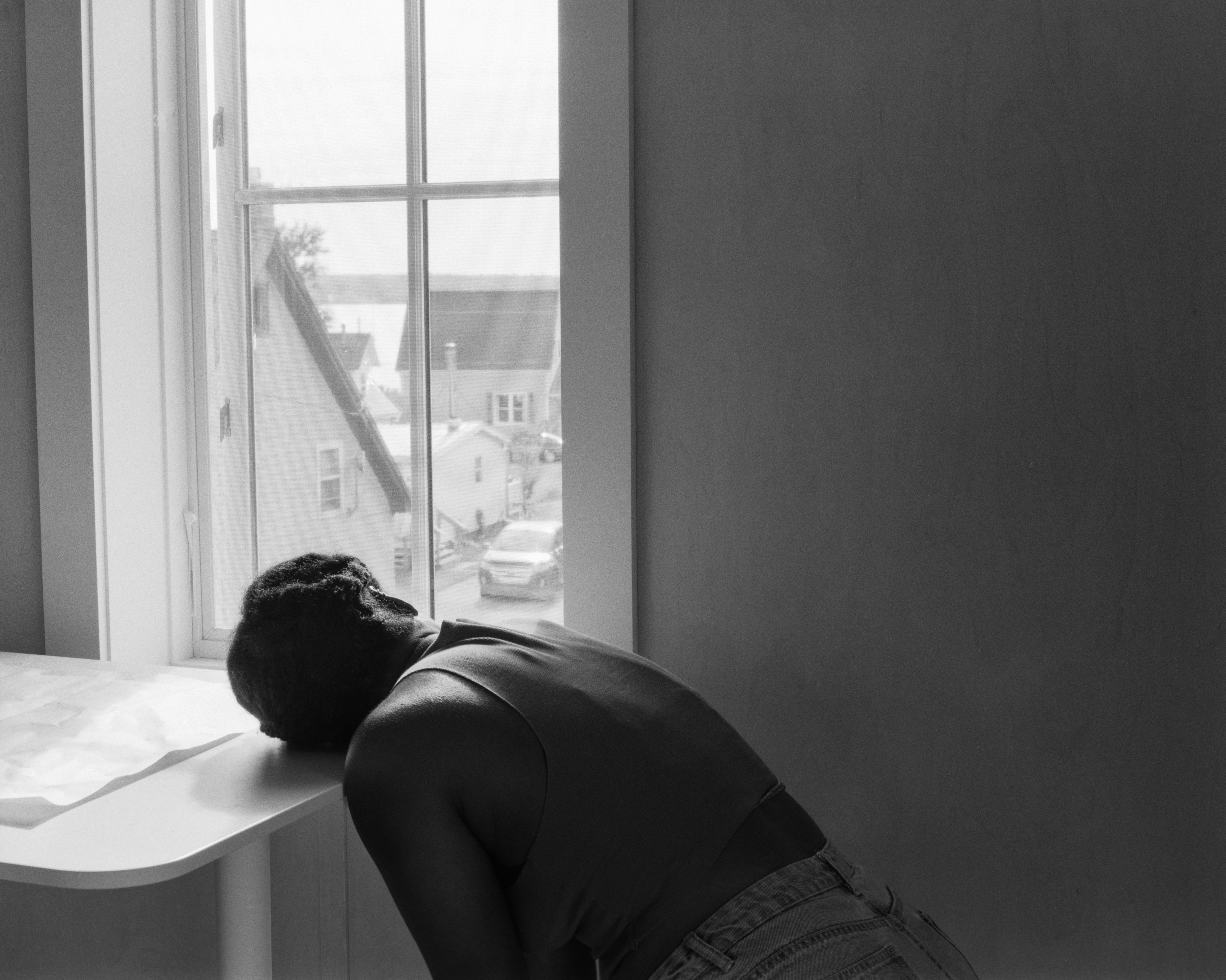 a table is in front a window and a person leans their head over 