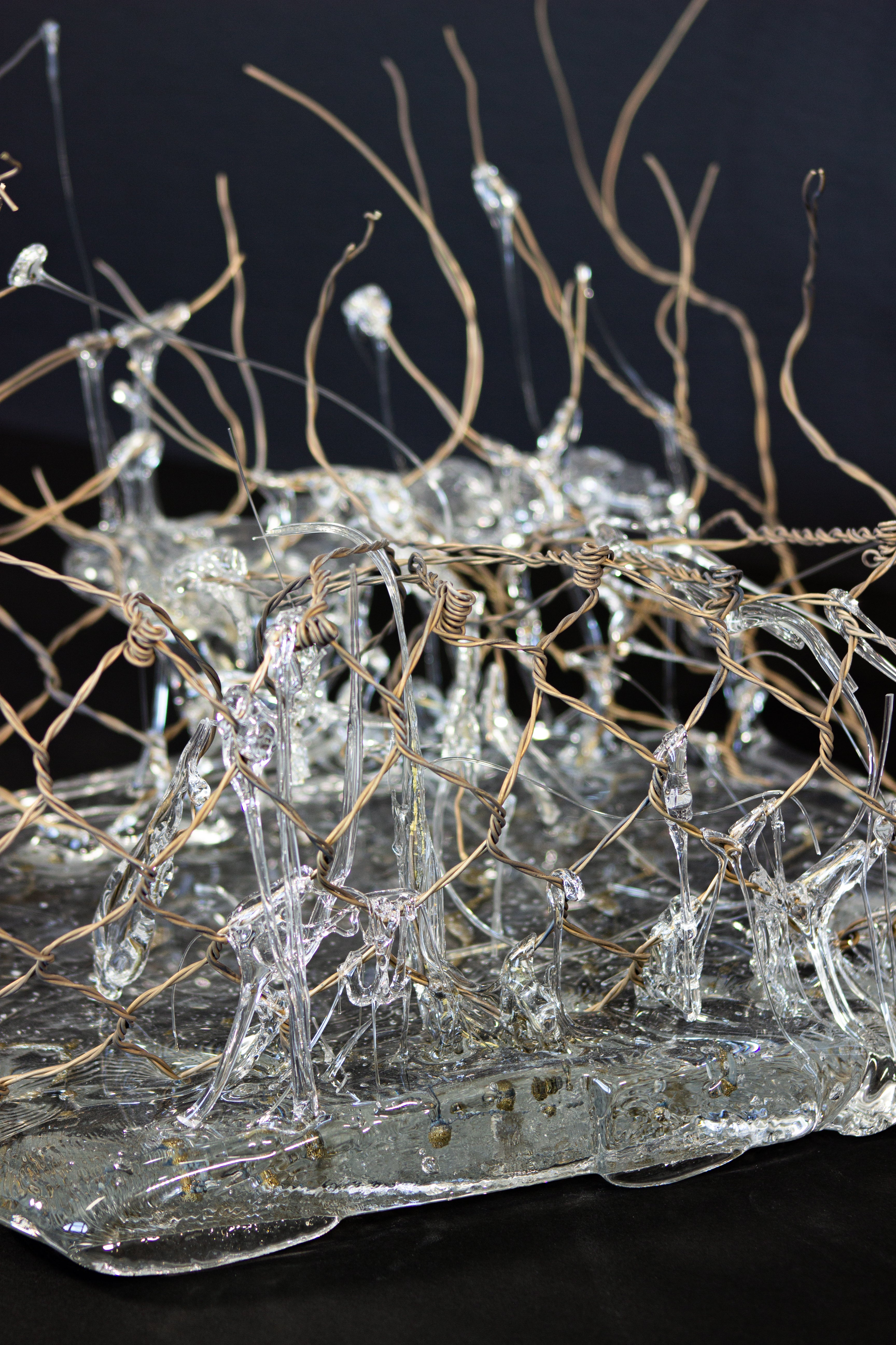 Piece of hand-woven chain-link fence with molten glass encasing some parts of it.