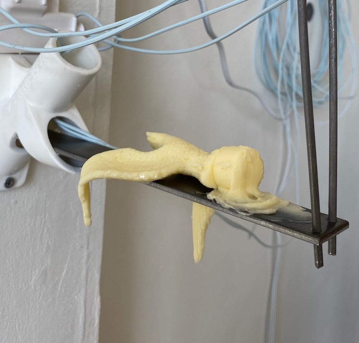 A miniature American eagle - made of butter - droops as it melts atop a steel bar.