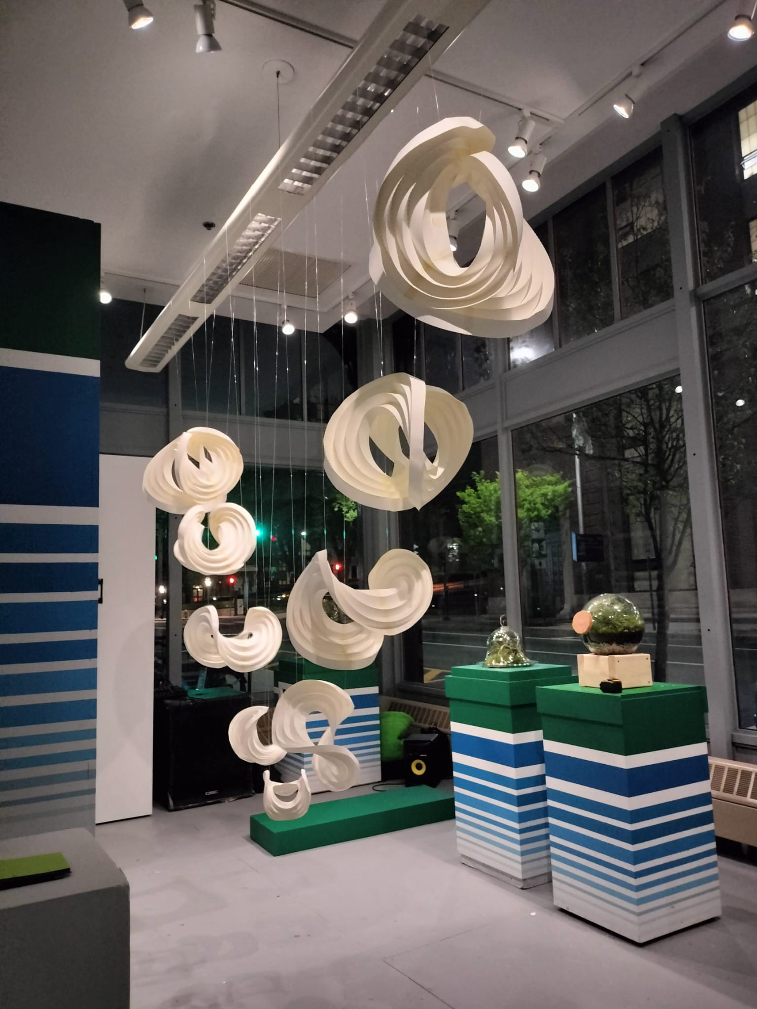 Suspended curved paper sculptures of varying sizes and heights.