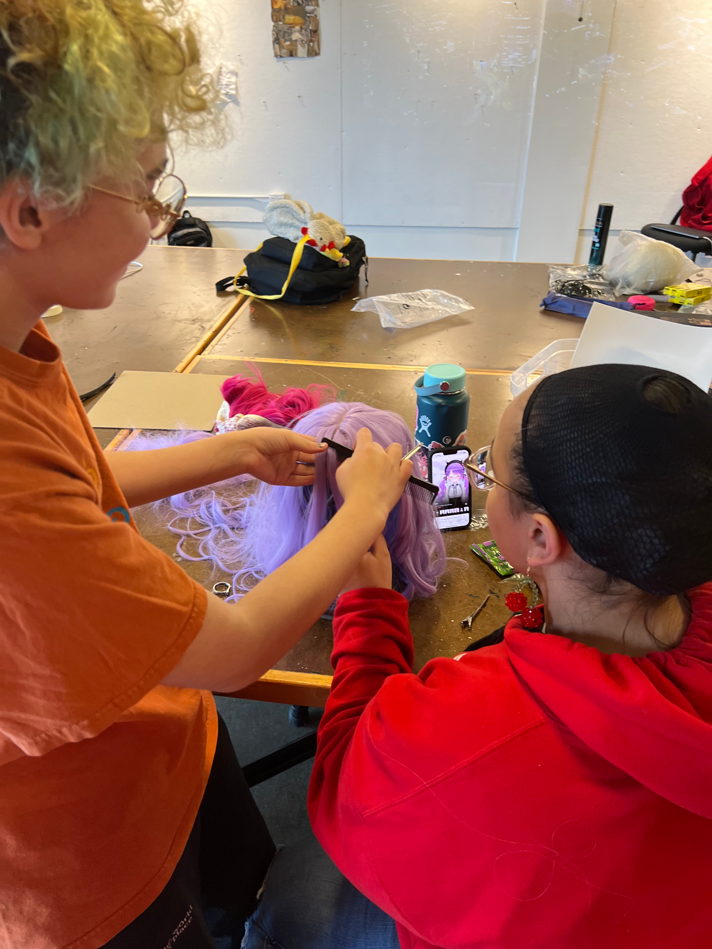 Student A and B from Project Open Door(POD) practicing styling a purple wig during Cosplay 101, a POD after-school program.