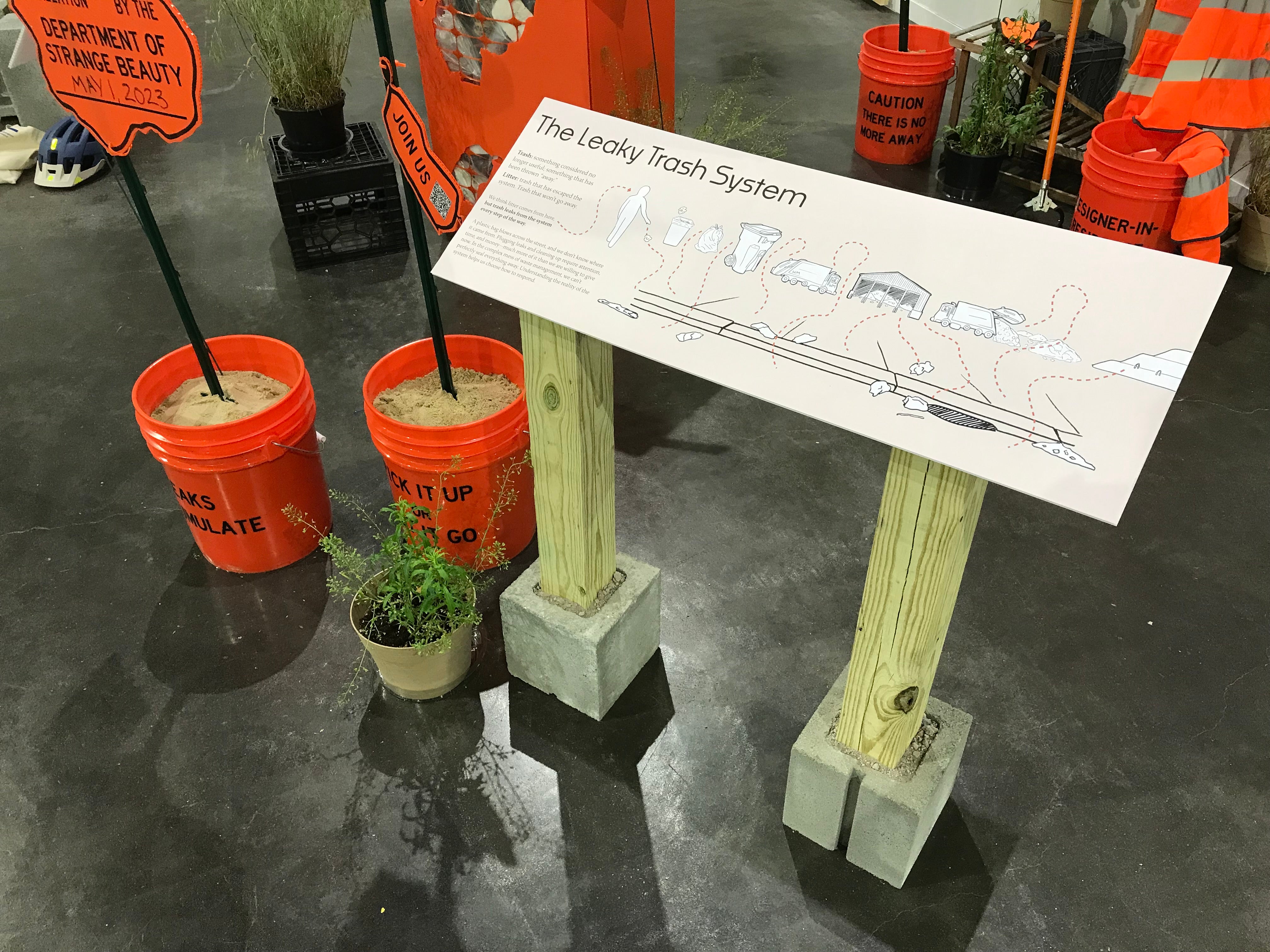 Diagram of the trash system, showing litter escaping at various points, posted on a board standing on wooden and concrete block legs.