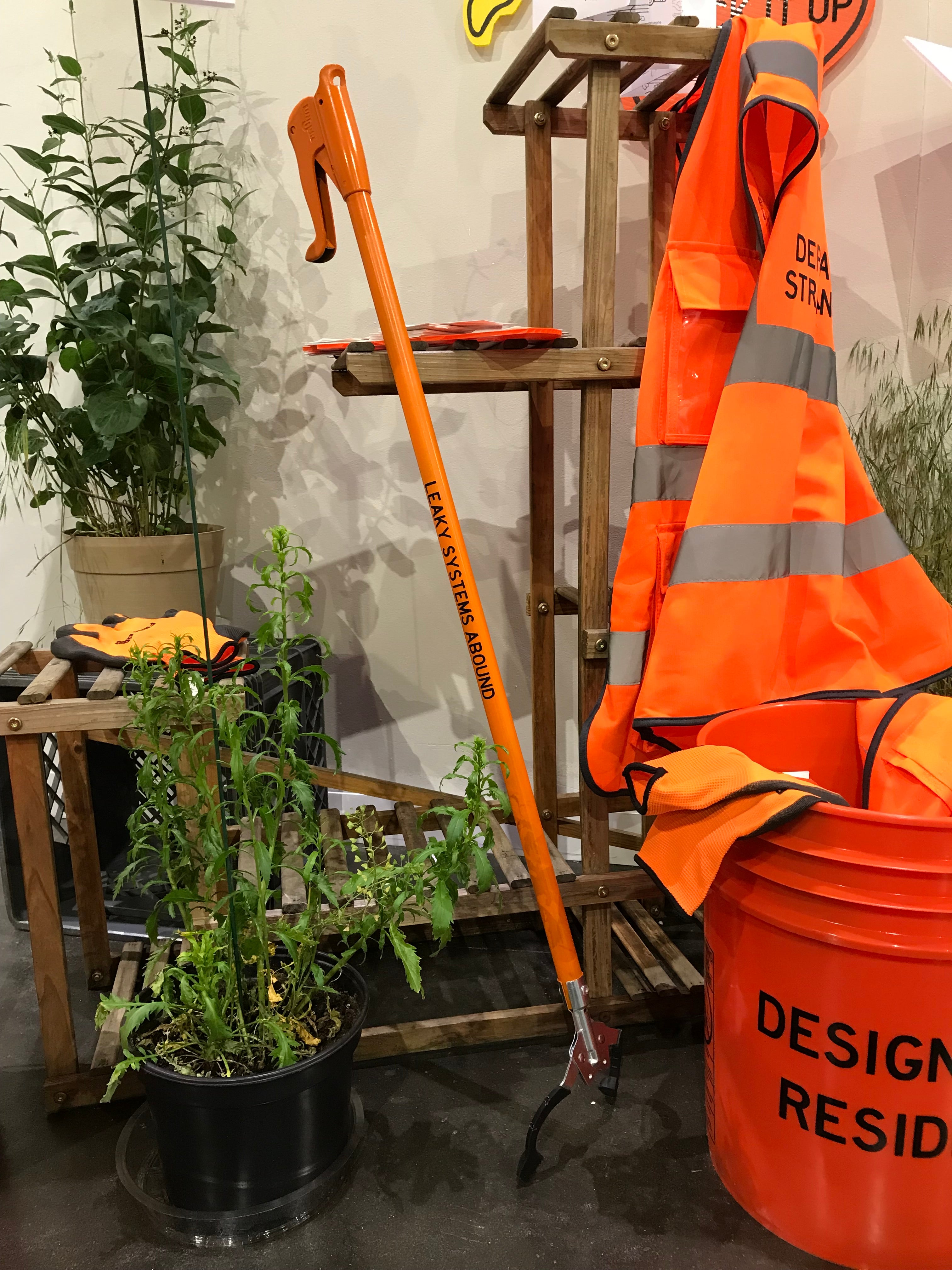 Installation view of a Designer-in-Residence Toolkit, including bucket, trash grabber, vest, pamphlet, clipboard, stickers, and gloves