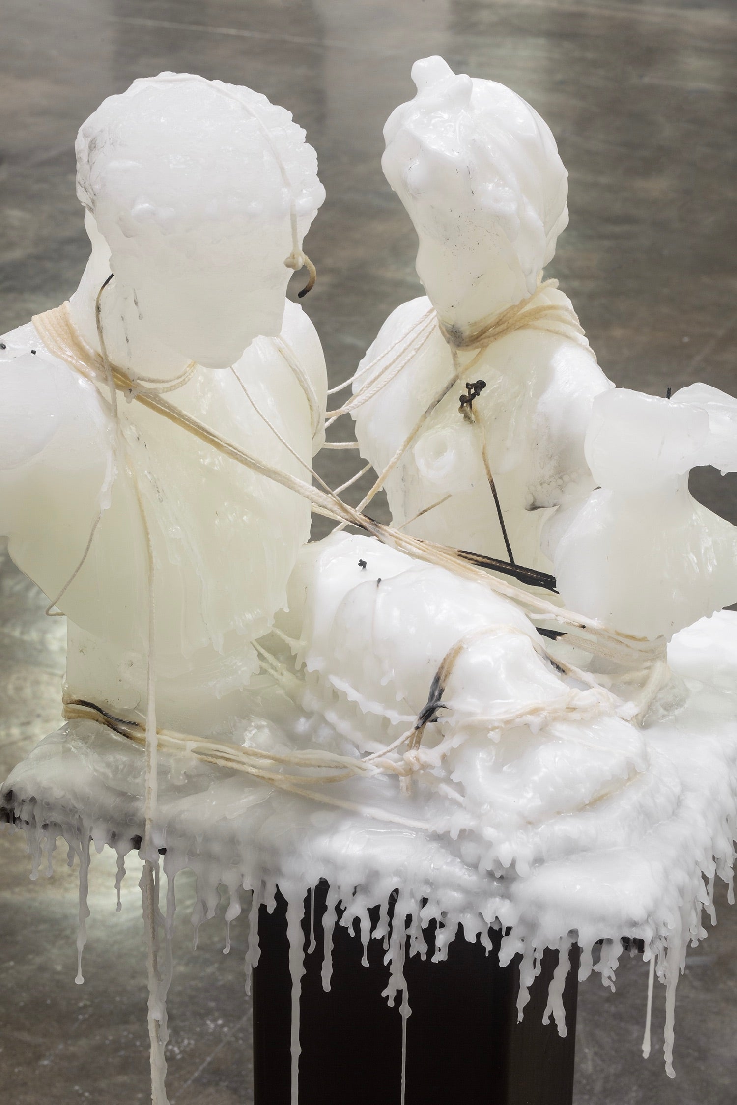 Detail of sculpture wax figures arranged and entangled with wicks.