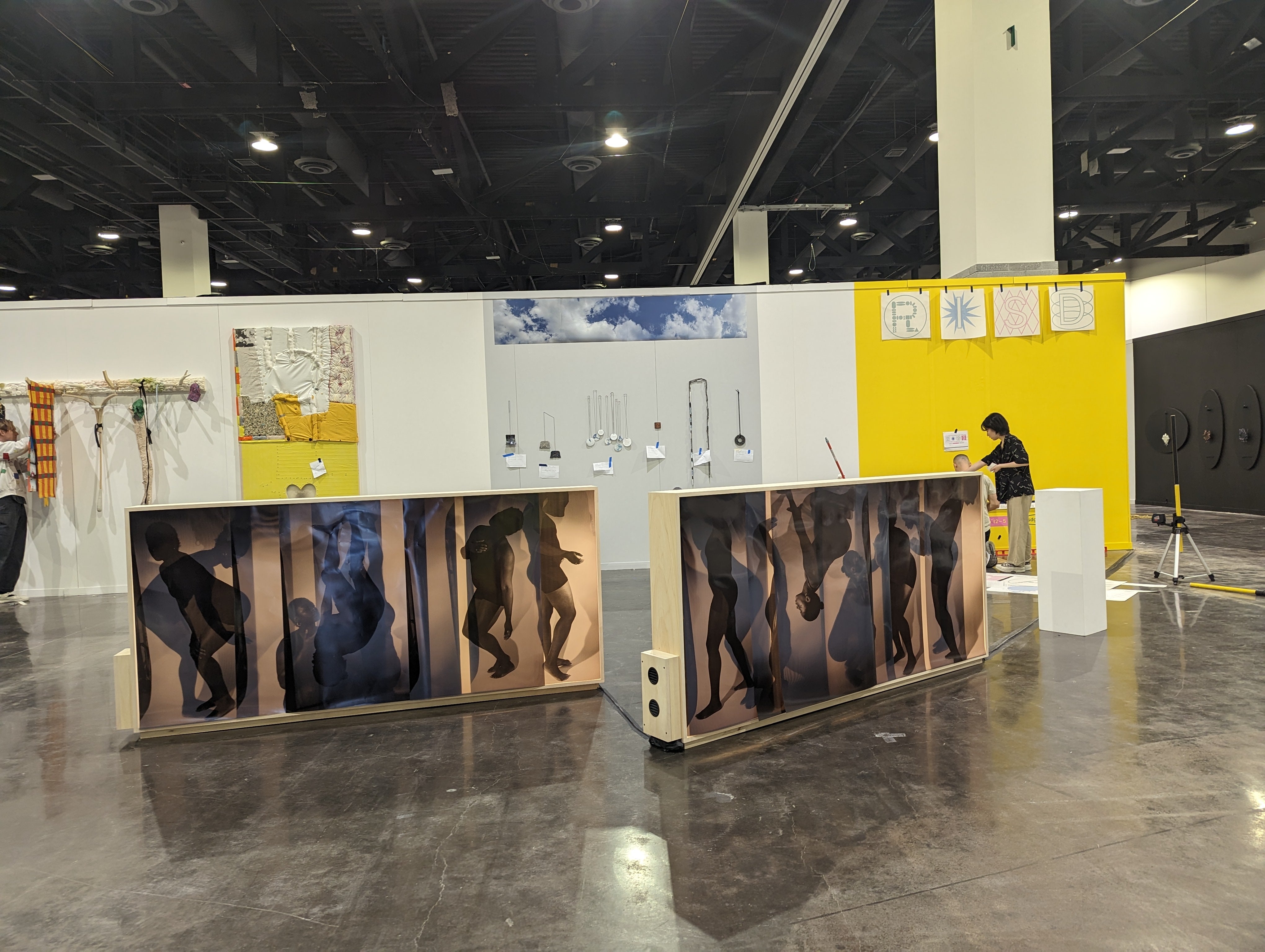 two large horizonal light boxes lit on both sides. one side has a silhouetted body making repeated gestures and the other in a person laying in a bed