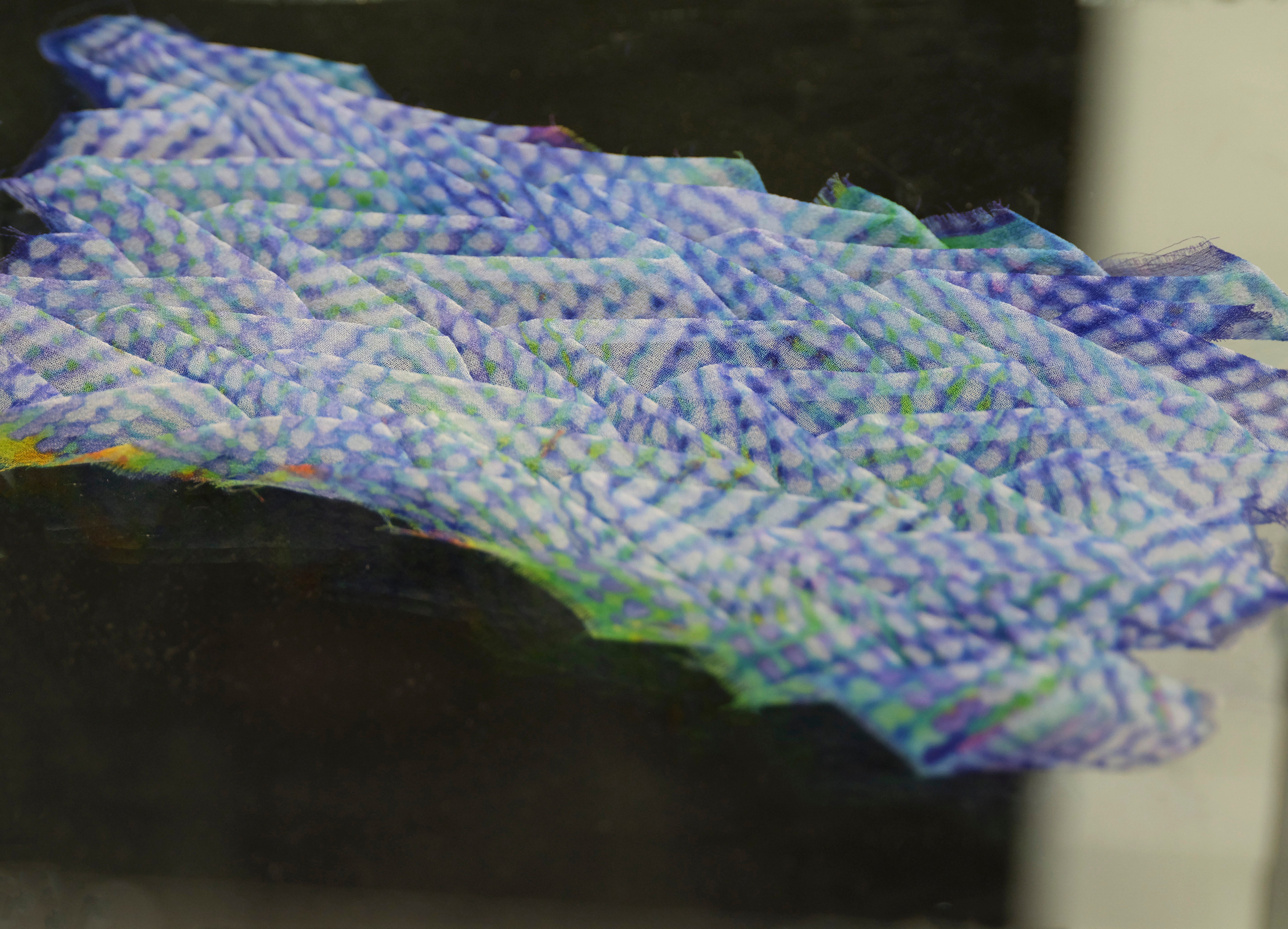 Detail shot of knitted technical structures sampler swatch on acrylic pedestal