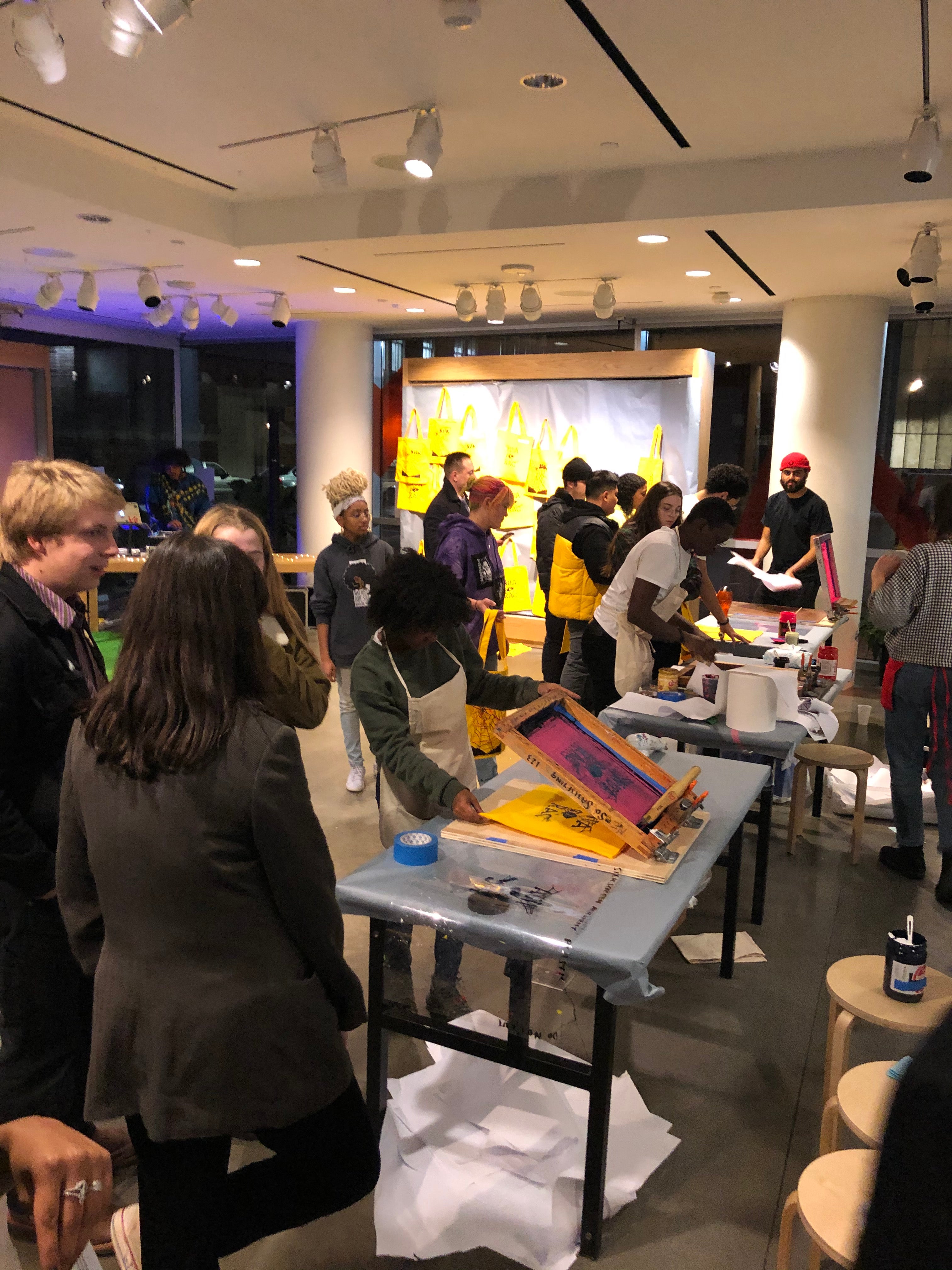 Crowd of teenagers in front of tables with screenprinting stations 