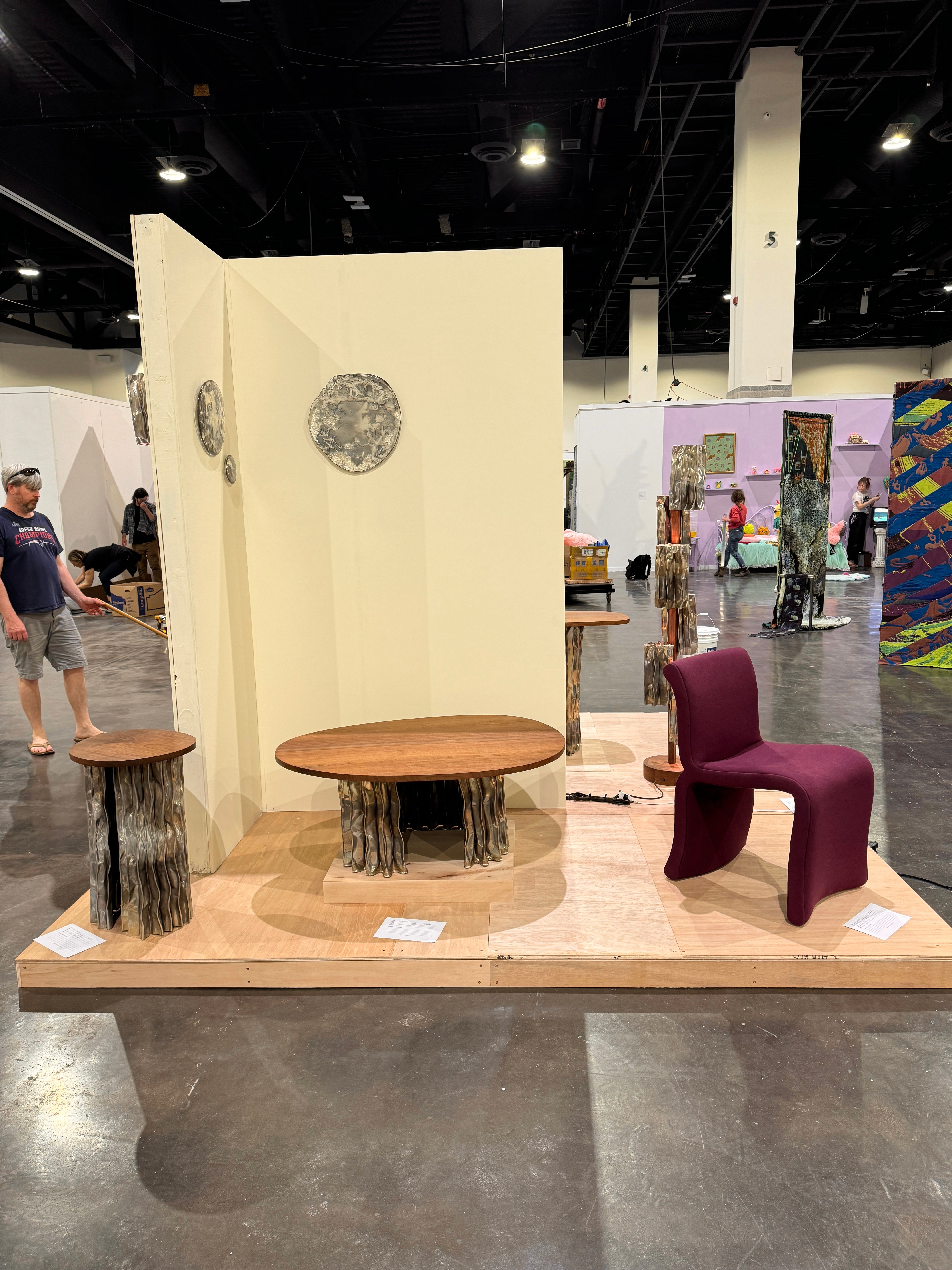 A modern furniture collection includes a coffee table, console table, pedestal table, and two floor lamps. The tables have an aluminum base and walnut tops. The floor lamps display decorative aluminum shades and central walnut stands.