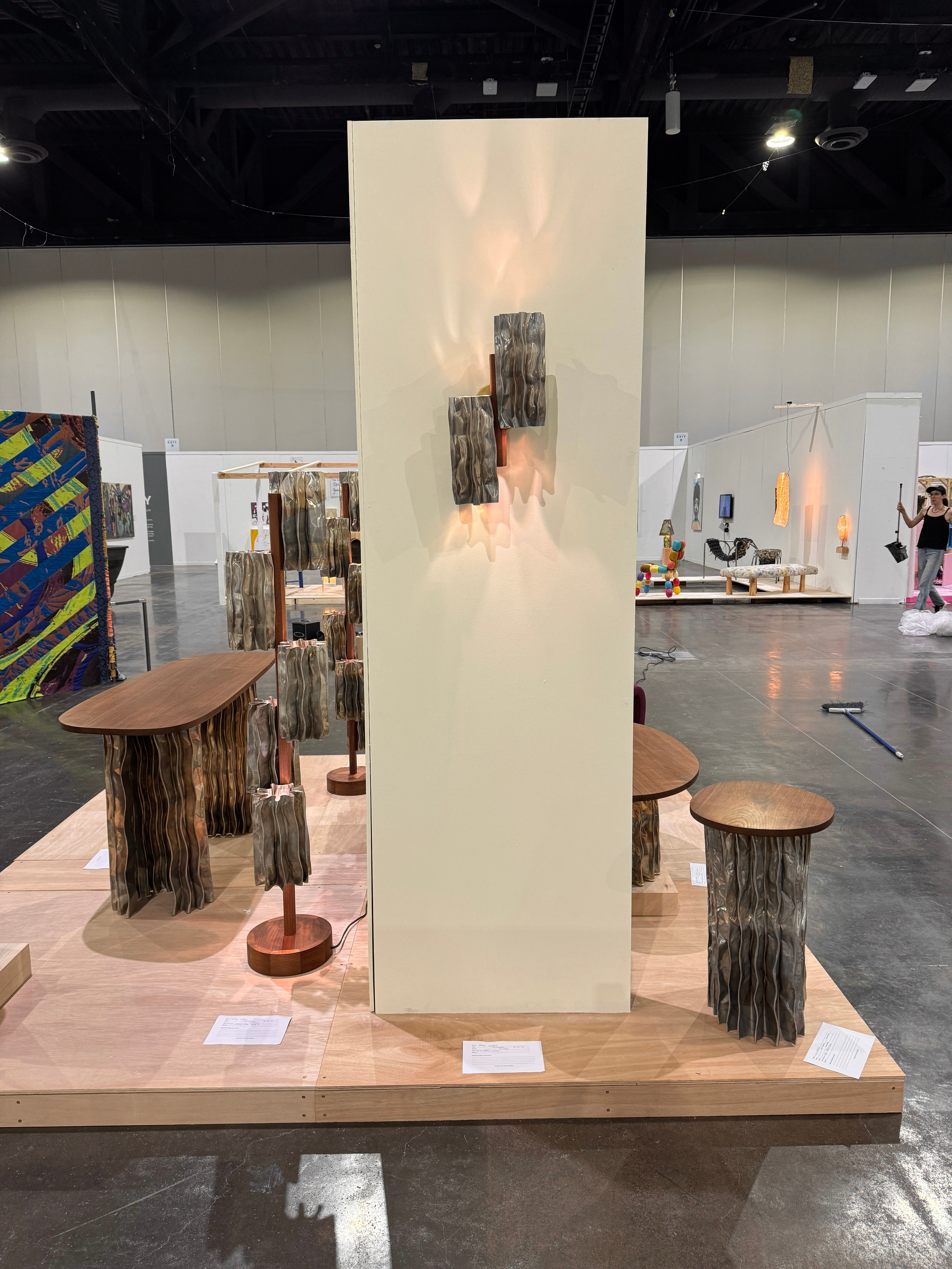 A modern furniture collection includes a coffee table, console table, pedestal table, and two floor lamps. The tables have an aluminum base and walnut tops. The floor lamps display decorative aluminum shades and central walnut stands.