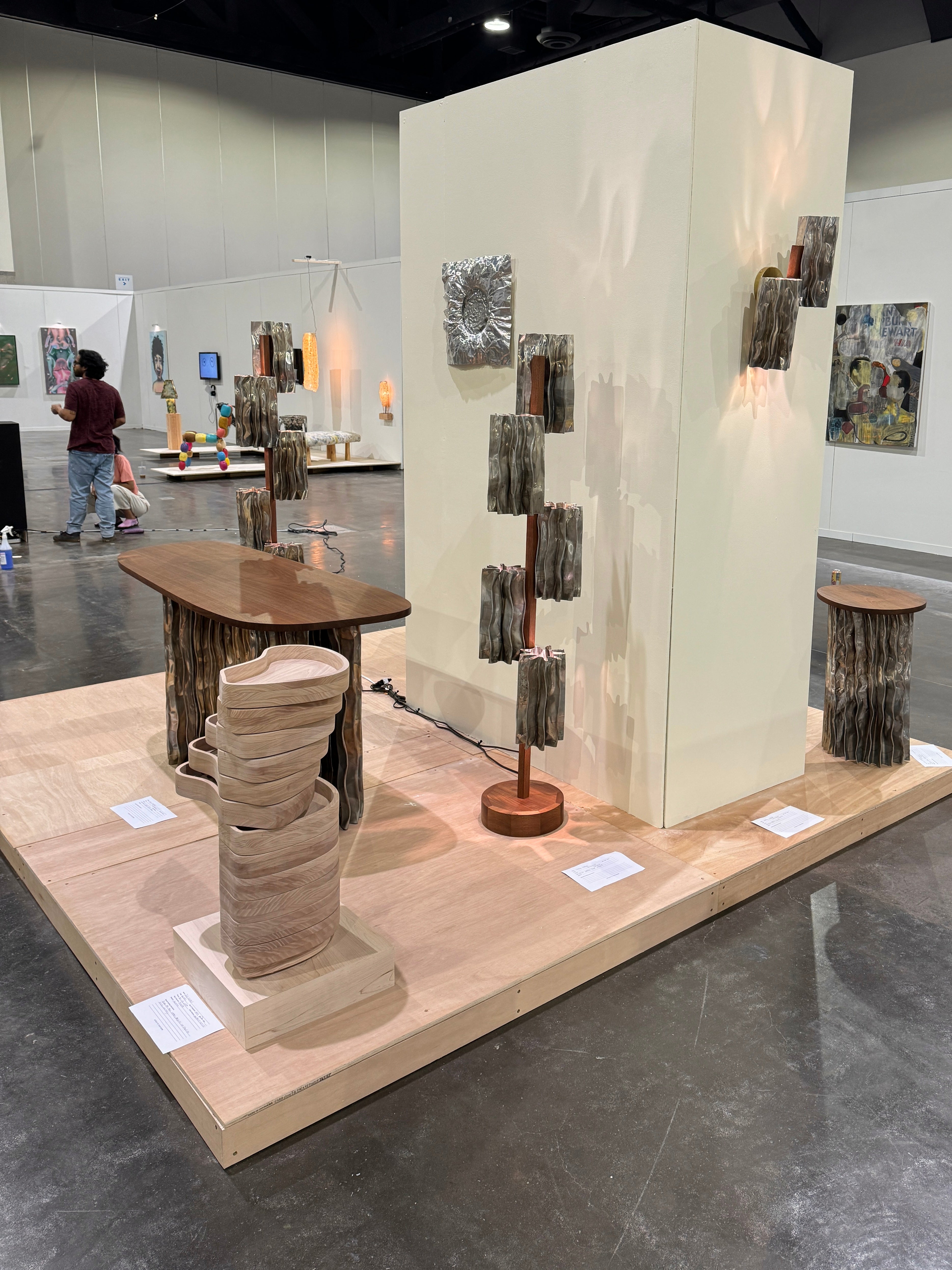 A modern furniture collection includes a coffee table, console table, pedestal table, and two floor lamps. The tables have an aluminum base and walnut tops. The floor lamps display decorative aluminum shades and central walnut stands.