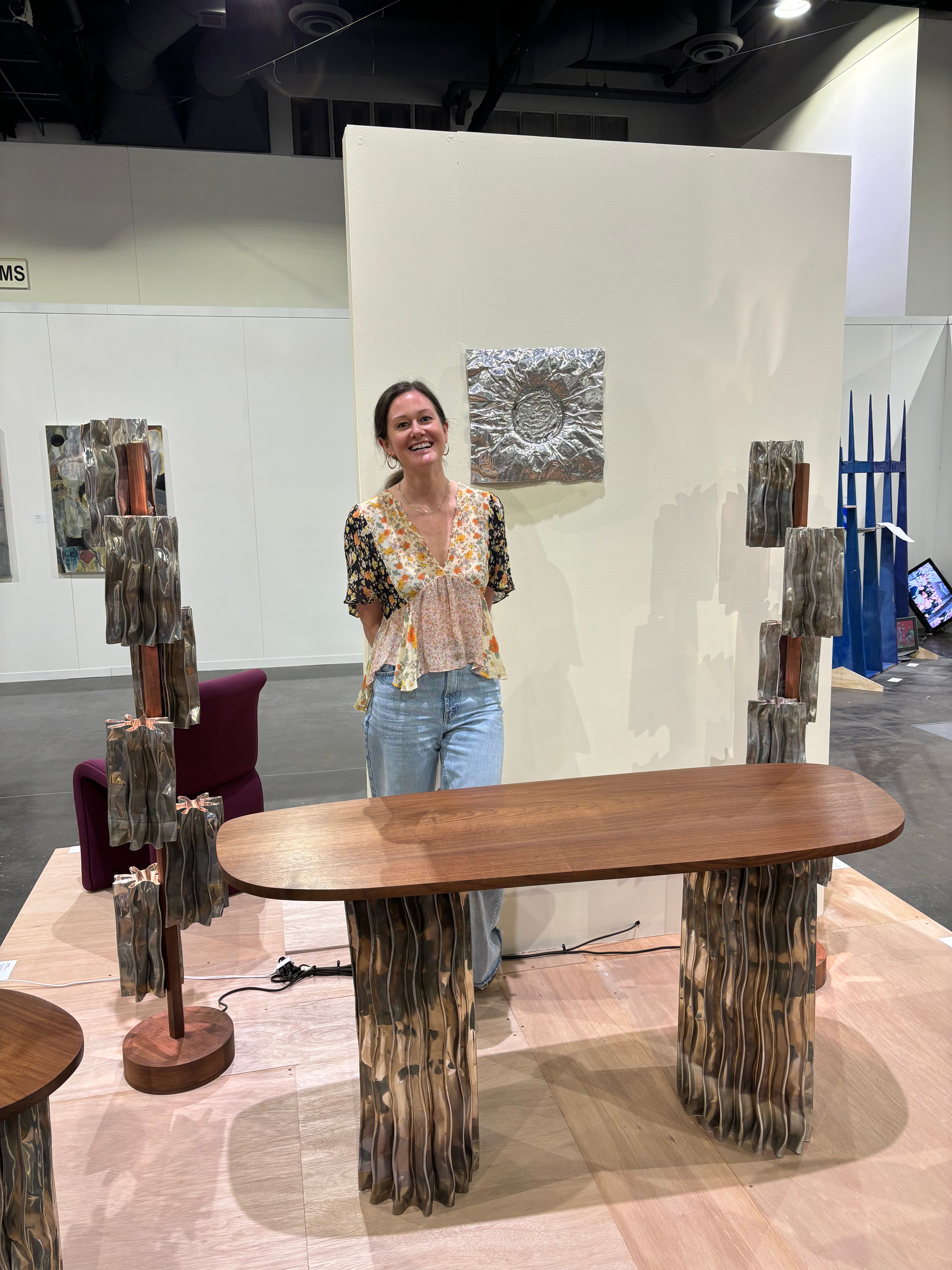 A modern furniture collection includes a coffee table, console table, pedestal table, and two floor lamps. The tables have an aluminum base and walnut tops. The floor lamps display decorative aluminum shades and central walnut stands.