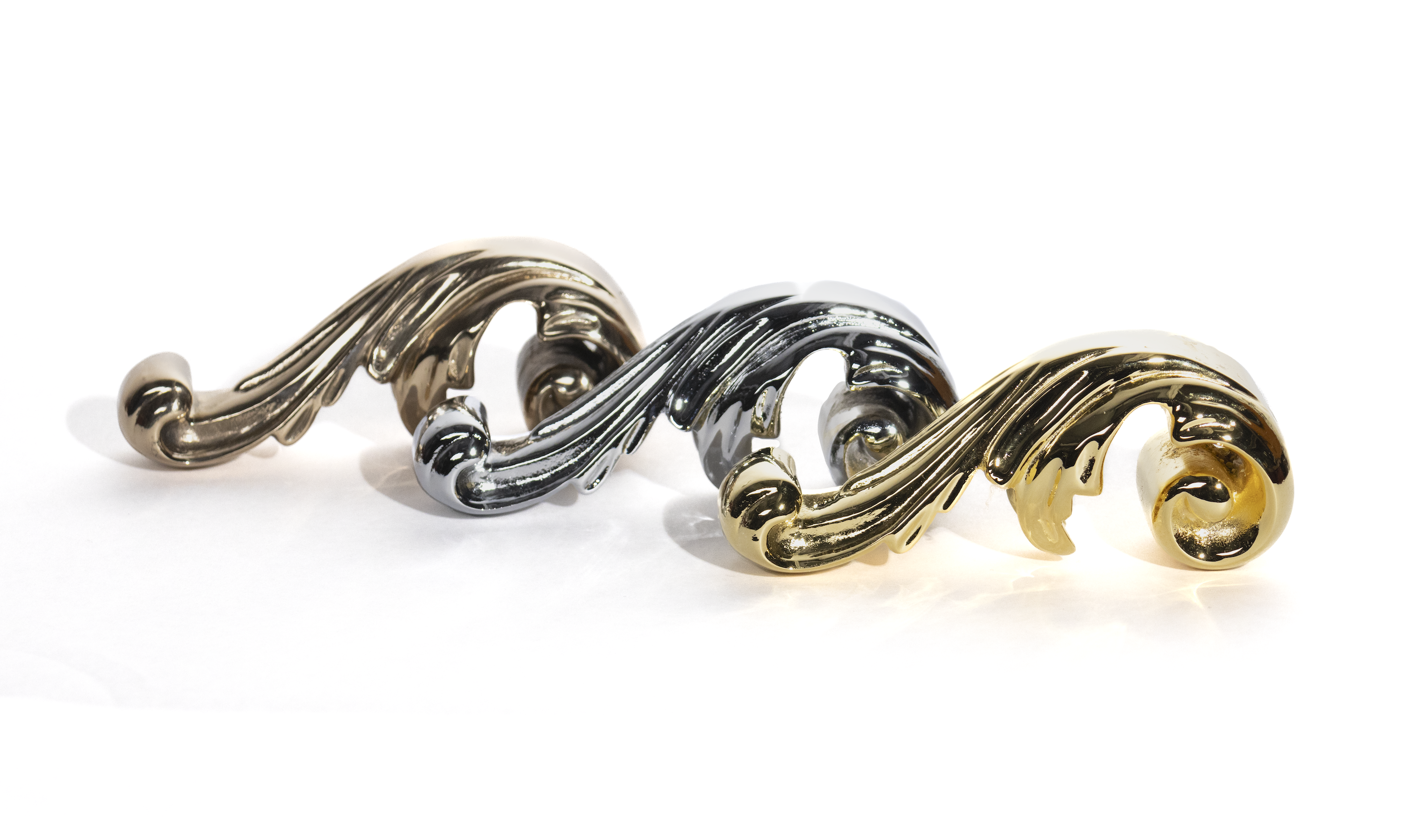 solid cast bronze acanthus leaf ornaments. Three are viewed from the side in line with eachother, one is polished bronze, one is gold-plated, one is chrome-plated
