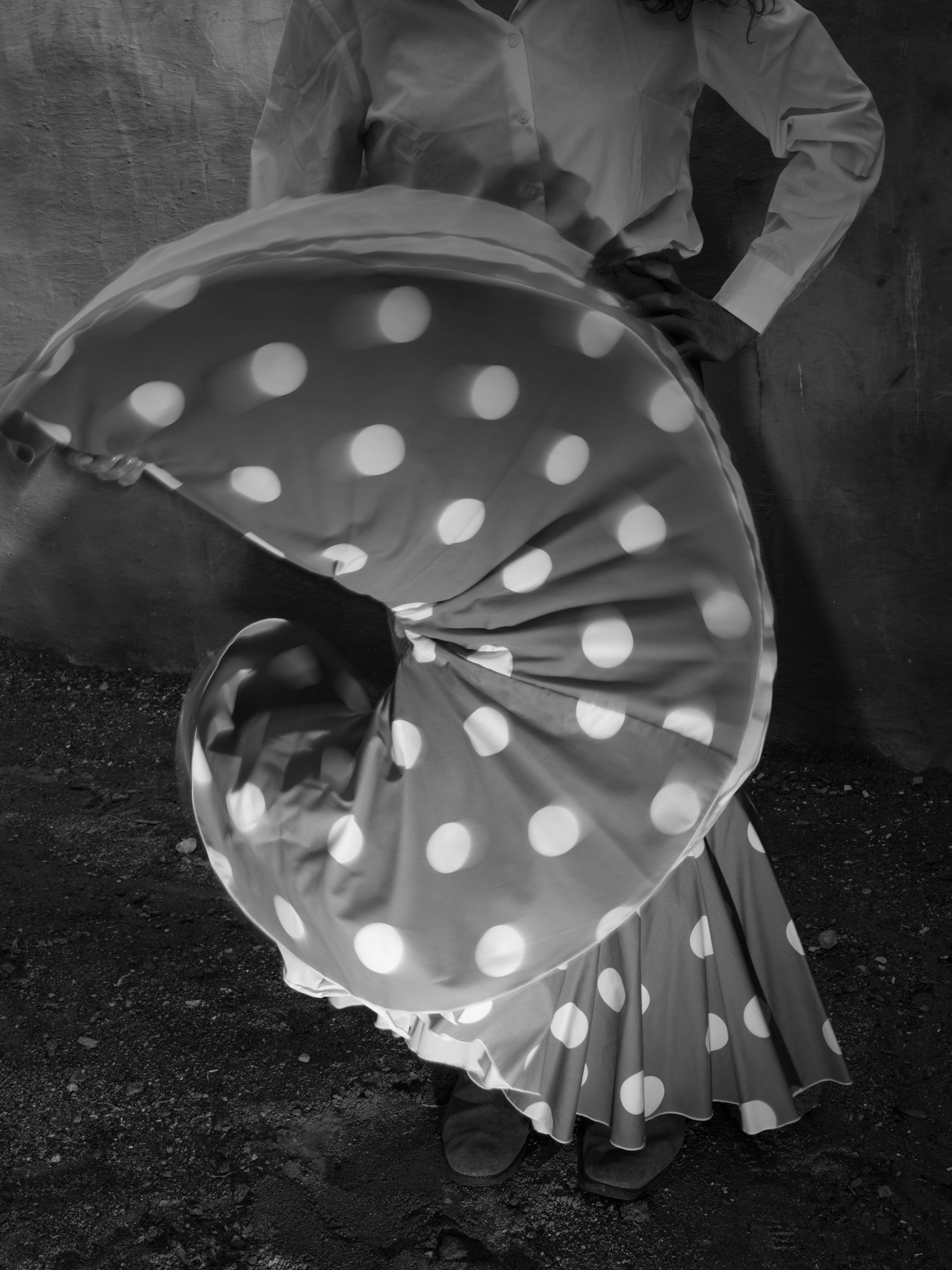 /Black%20and%20white%20photograph%20of%20a%20person%20with%20a%20skirt%20full%20of%20white%20dots%2C%20which%20they%20are%20undulating%20with%20one%20hand%20for%20the%20picture%20