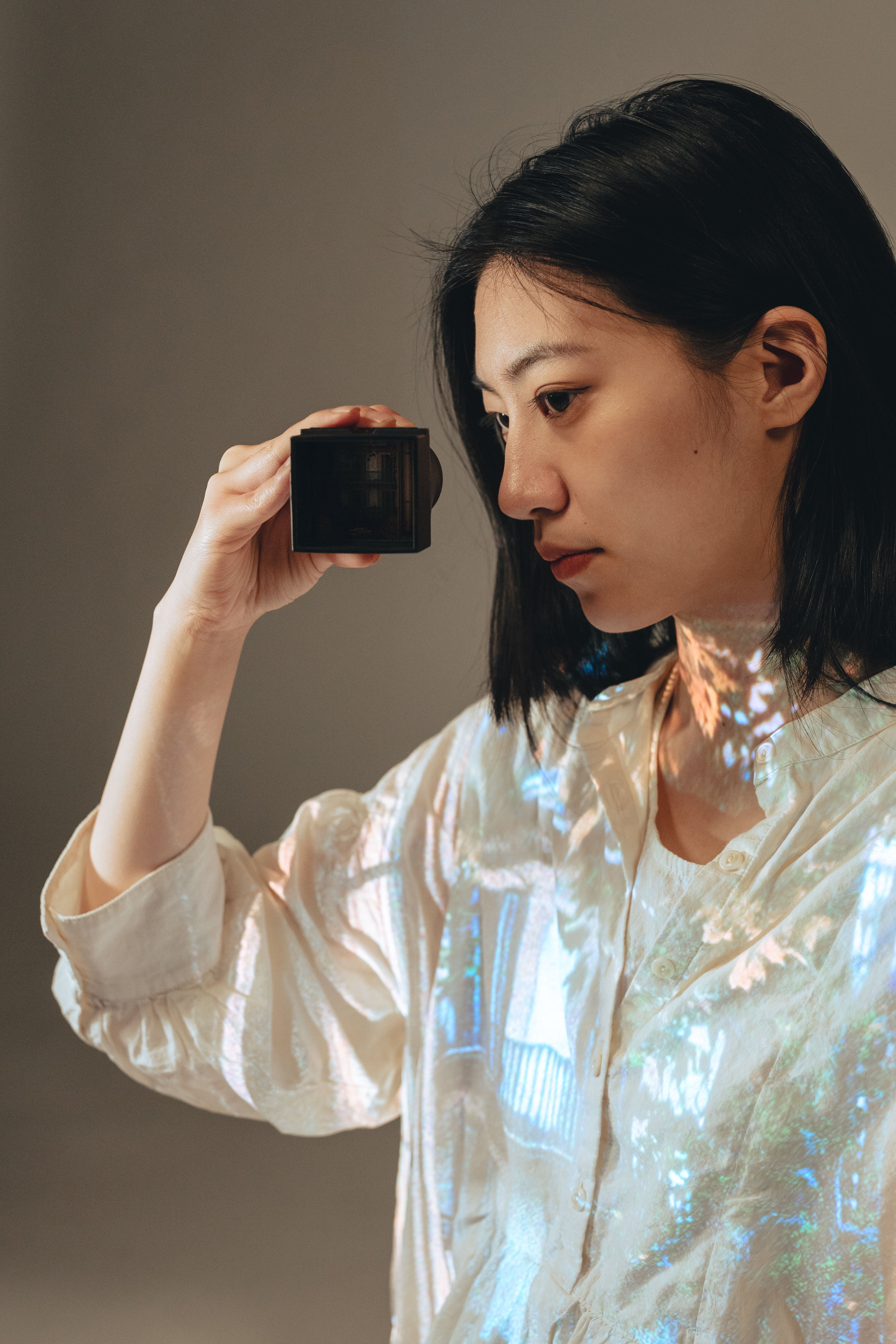 /A%20girl%20is%20looking%20through%20a%20lens%20that%20has%20a%20projection%20inside.%20In%20one%20of%20her%20clothes%2C%20a%20corresponding%20image%20is%20projected.