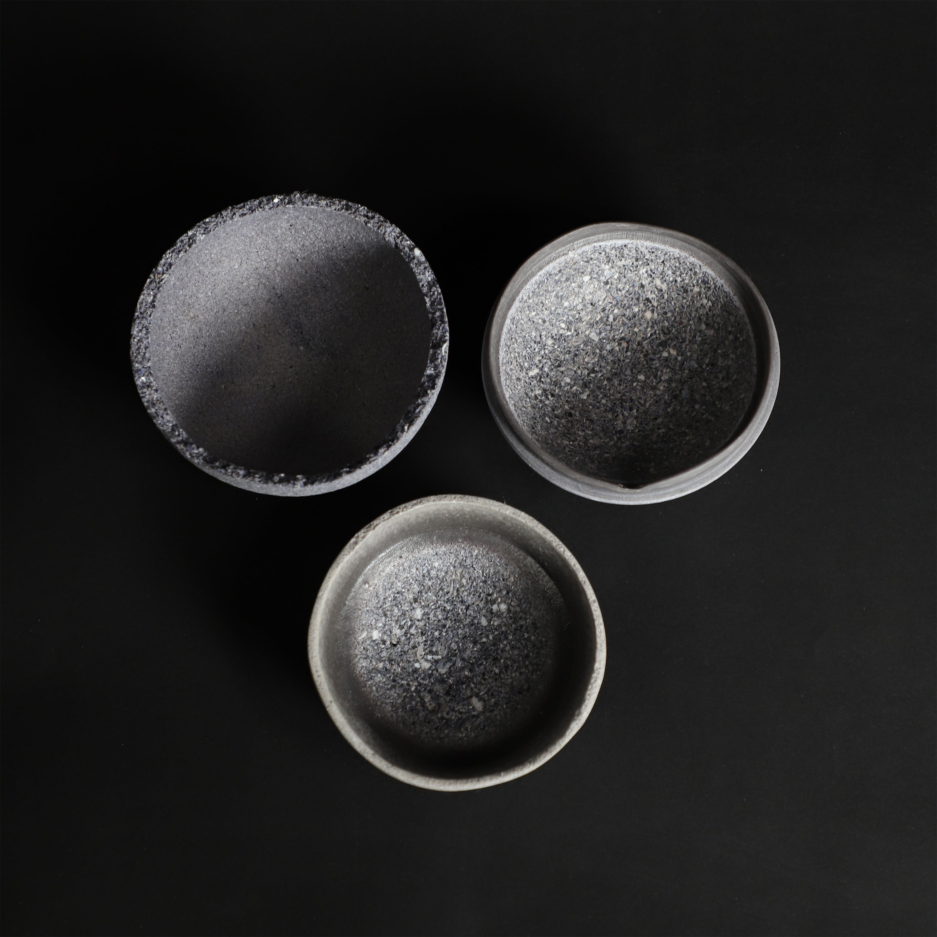 /Three%20shallow%2C%20round%20bowls%20made%20from%20mussel%20shells%2C%20arranged%20in%20descending%20size%20on%20a%20black%20background.%20The%20bowls%20have%20textured%2C%20dark%20blue%20exterior%20surfaces%20and%20smooth%2C%20light%20gray%20and%20blue%20interior%20finishes.