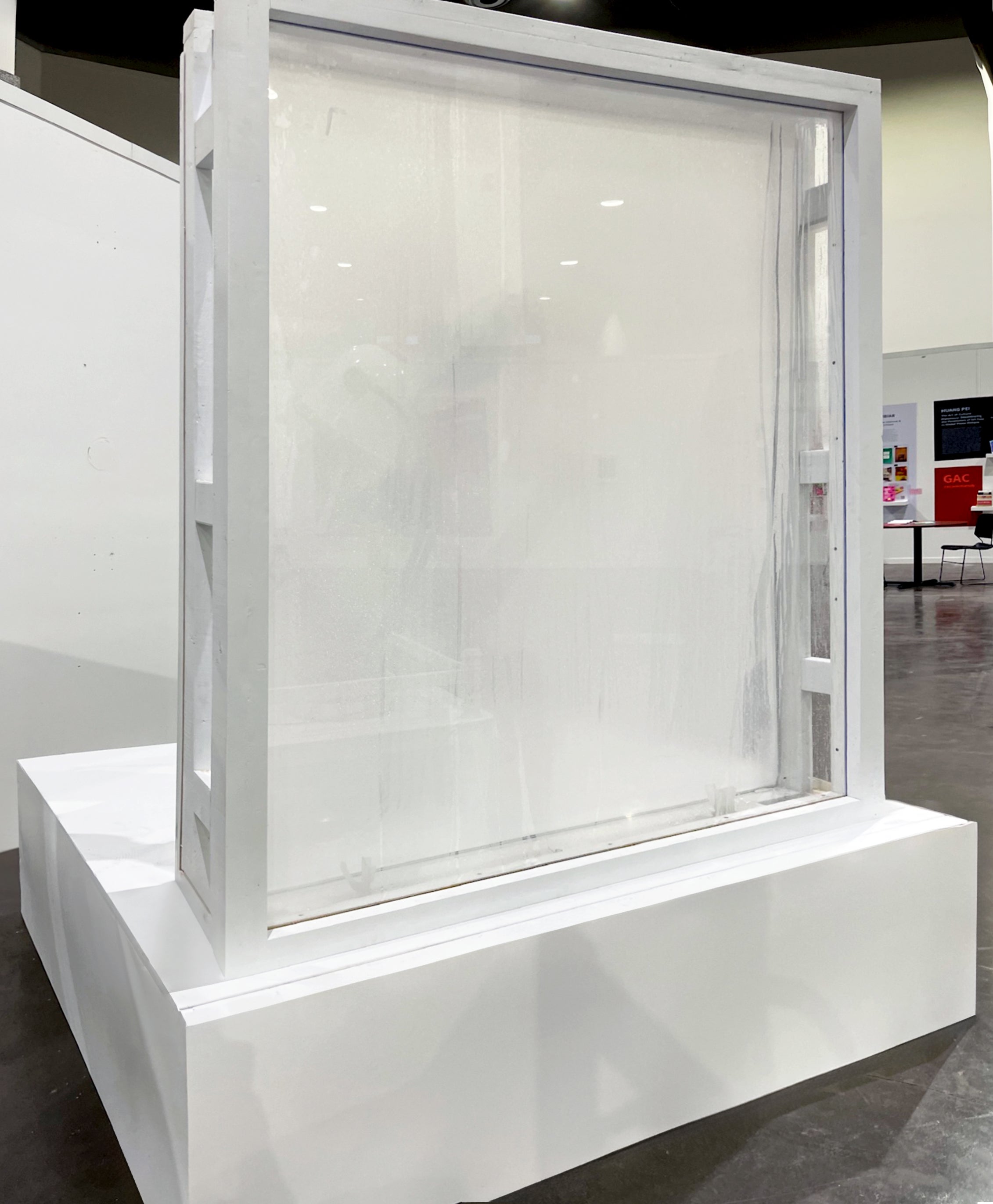 A white square stage with a window erected on one edge, with white frames and fog and condensation obscuring visibility. 