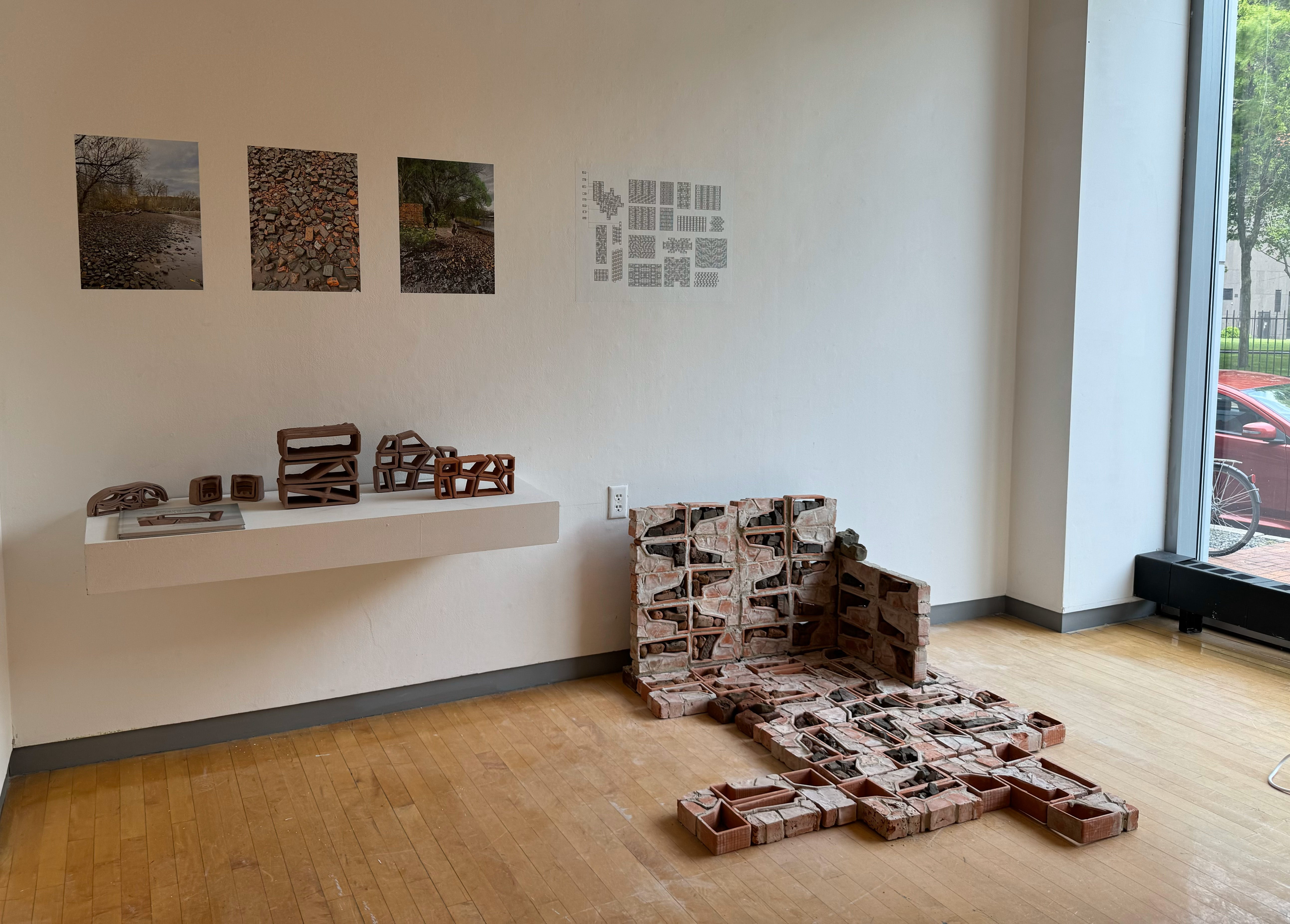 Image shows installation of brick wall, a floating shelf with several conceptual models. Drawings on the wall include the beach at Kingston Point, my perspective rendering, and the alternative modular possibilities of the system.