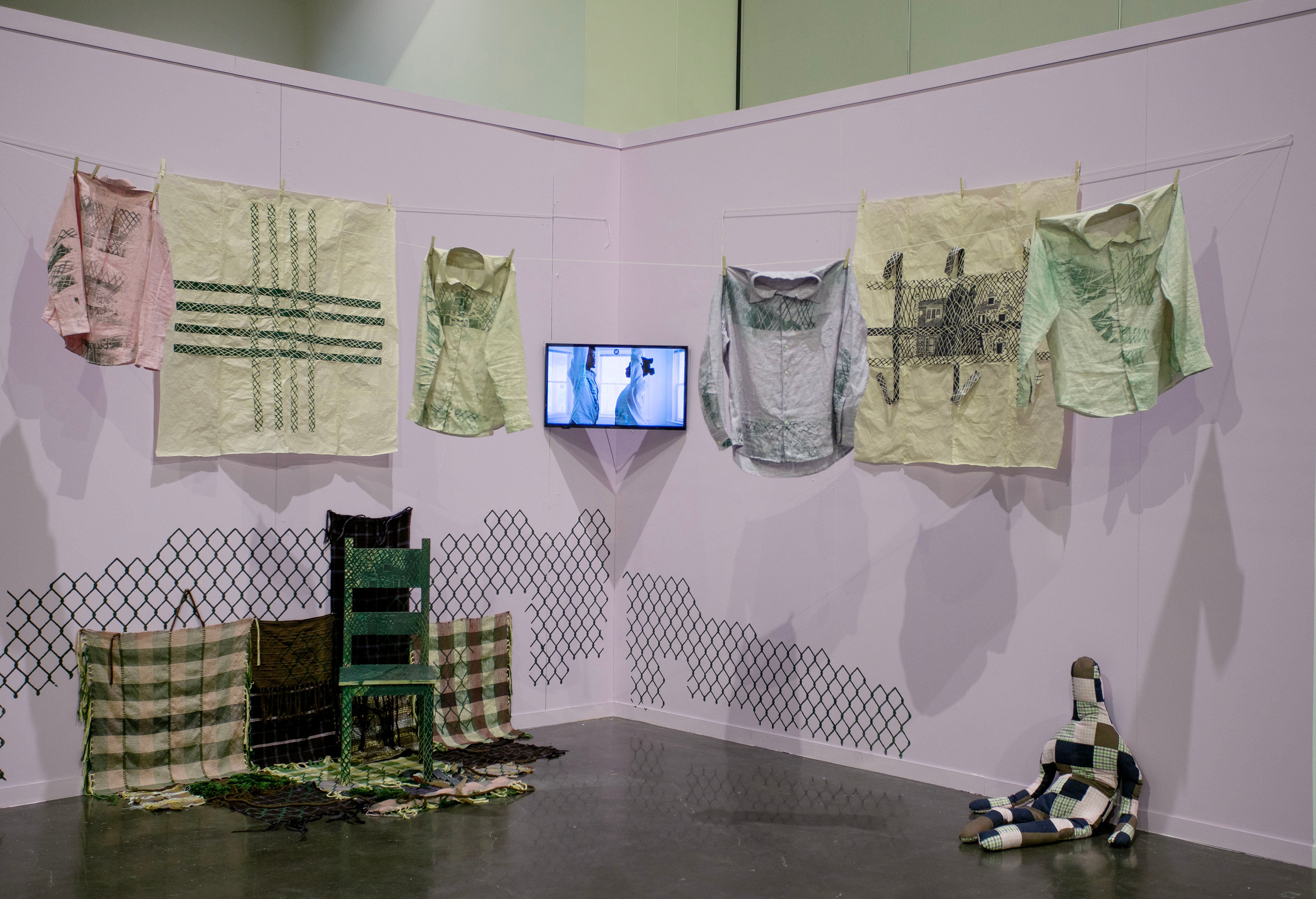 /Image%20of%20printed%20clothes%20hanging%20from%20clothesline%2C%20video%20performance%2C%20woodcut%20prints%2C%20carved%20chair%2C%20woven%20fabrics%2C%20and%20stuffed%20doll
