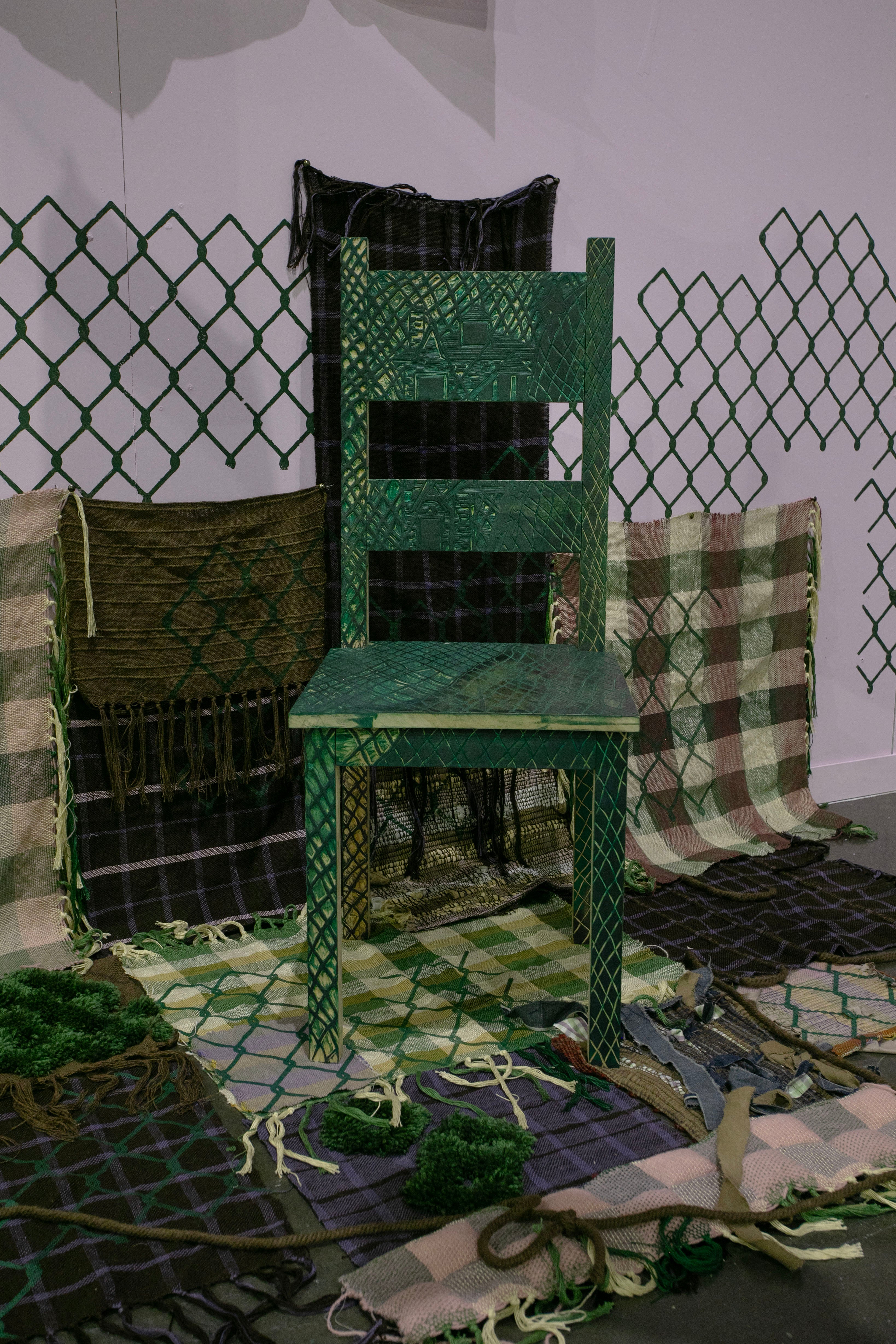 /image%20of%20carved%20green%20chair%20standing%20on%20top%20of%20woven%20fabrics%20travelling%20from%20the%20wall%20to%20the%20floor%20with%20chainlink%20motif%20printed%20on%20top%20with%20purple%20background