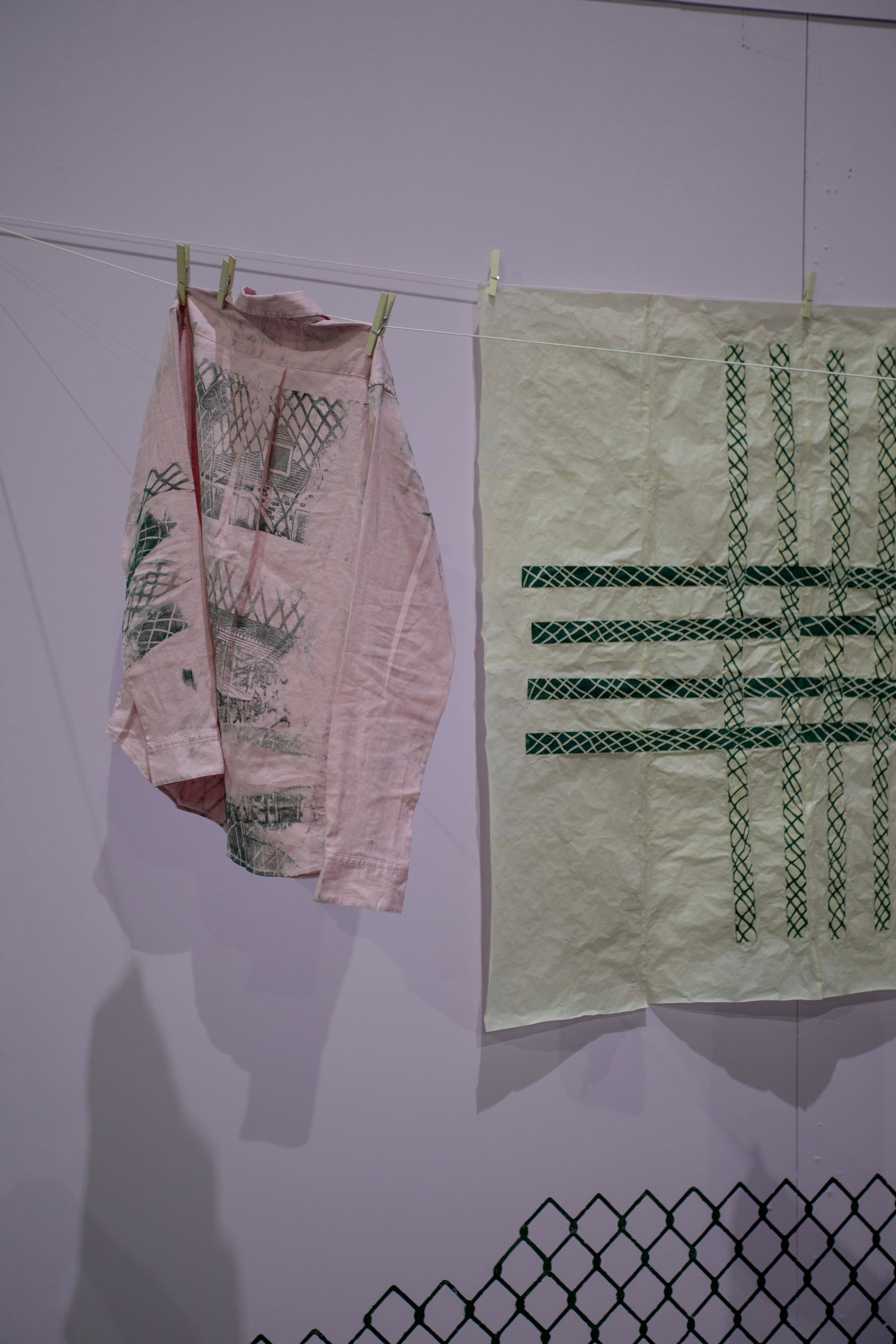 /pink%20shirt%20with%20green%20woodcut%20prints%20depicting%20a%20house%20and%20intersecting%20lines%20