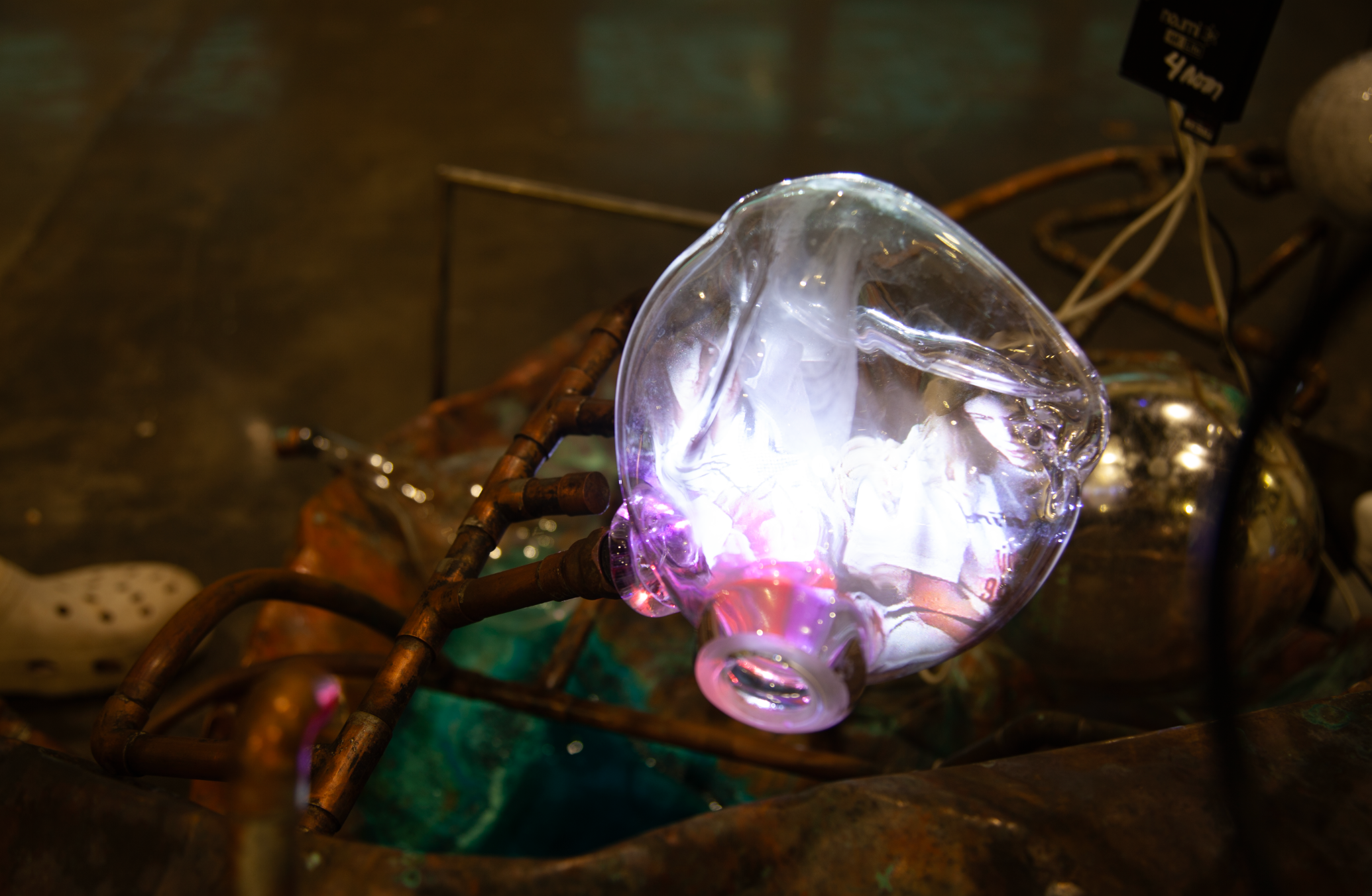 /bright%20glass%20with%20abstract%20color%20glowing%20on%20it%20with%20copper%20pipes%20intertwined%20behind%20it.%20a%20green%20patina%20is%20on%20the%20copper%20as%20well