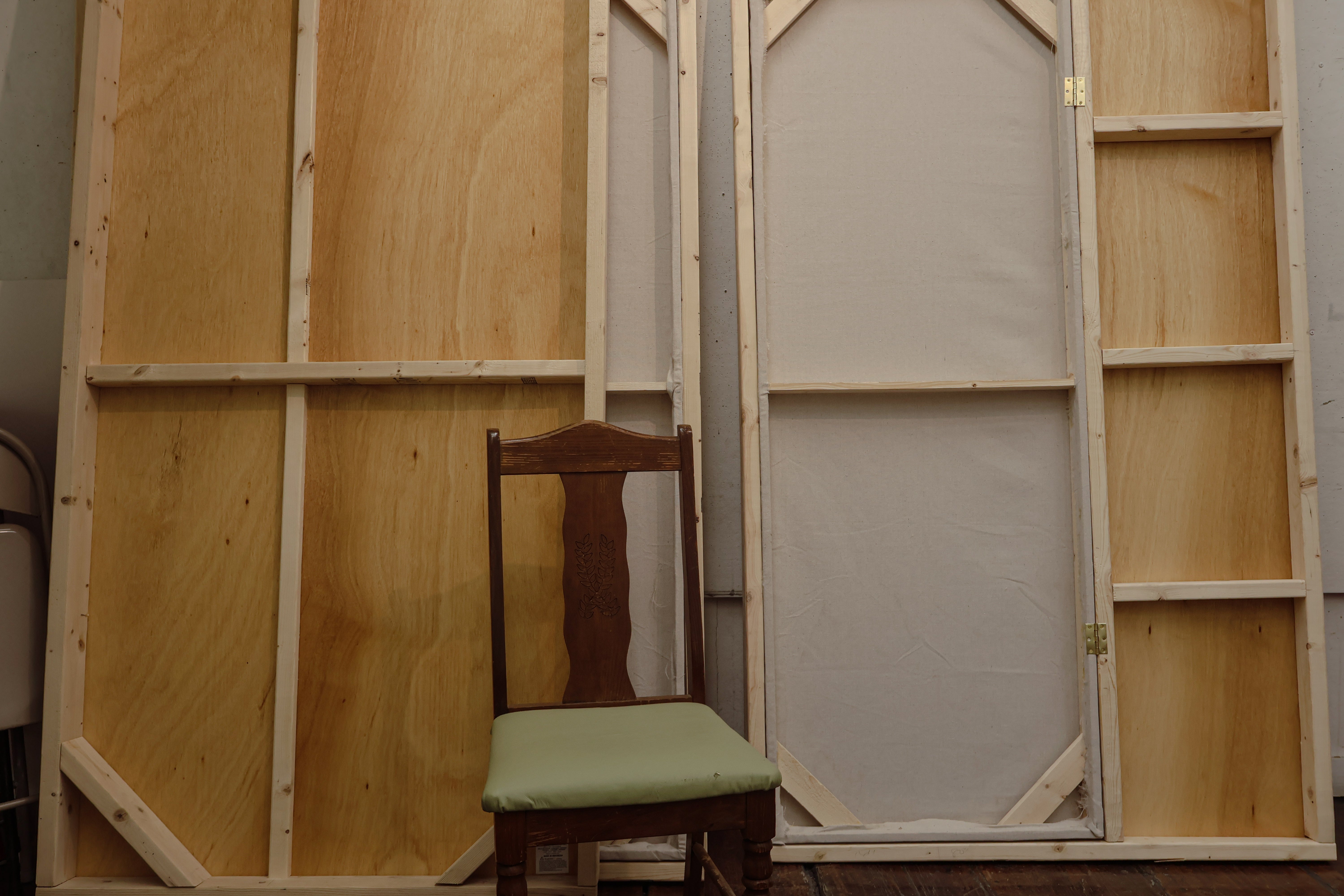 /Image%20of%20deconstructed%20walls%20that%20make%20up%20the%20thesis%20booth%20-%20made%20of%20wood%20and%20cloth%2C%20with%20a%20wooden%20chair%20in%20front