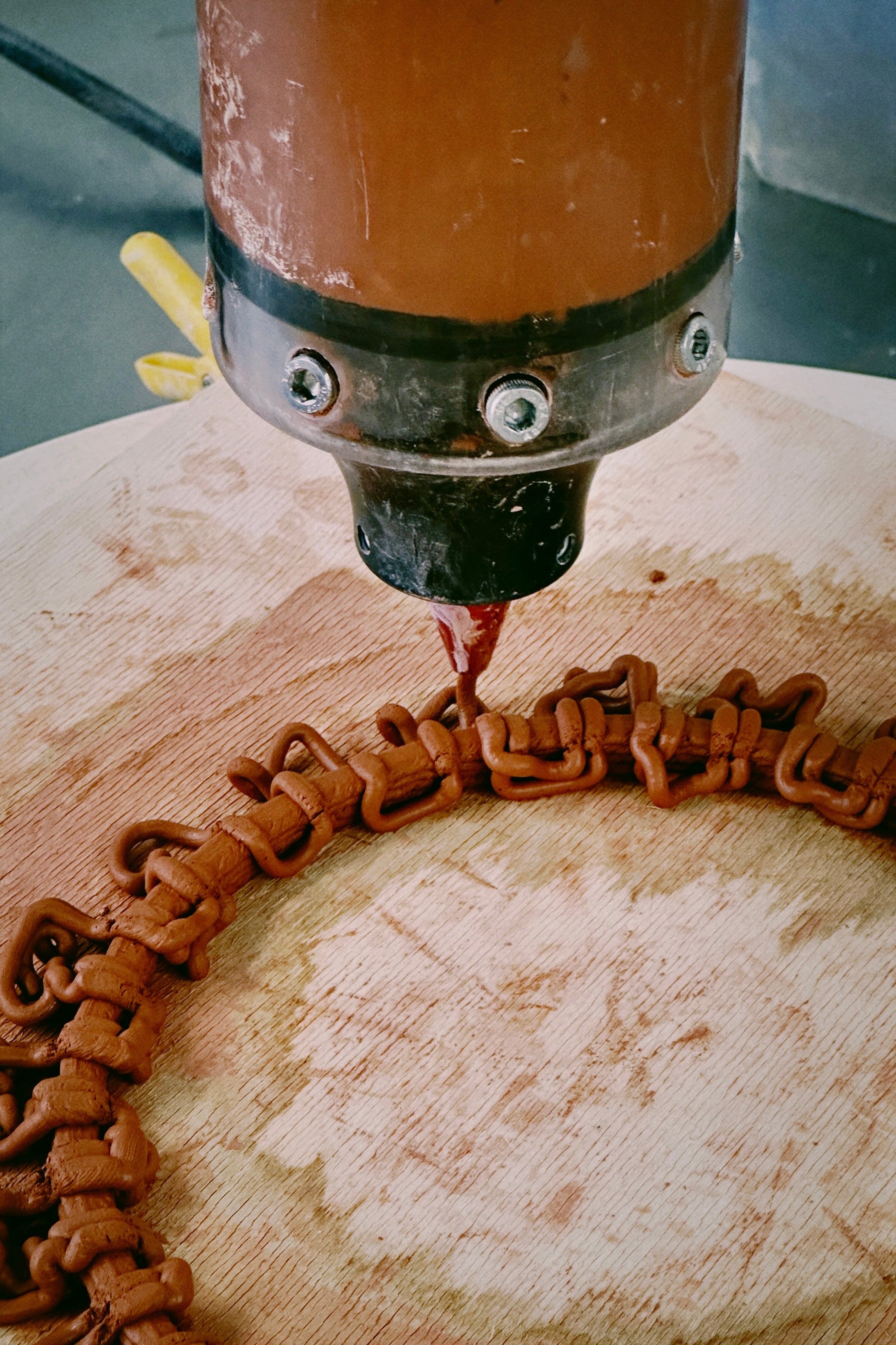 /Close-up%20of%20a%203D%20printer%20nozzle%20extruding%20intricate%20clay%20patterns%20on%20a%20rotating%20wooden%20platform.